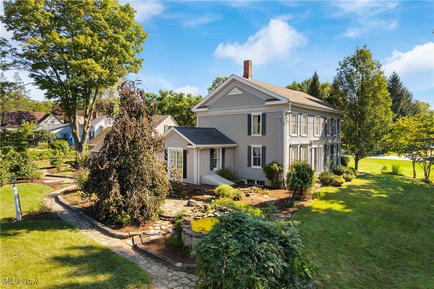 Welcome to 7009 Greenwich Road in Westfield Center—a Georgian Colonial built in 1837 that beautifully blends historic charm with modern comfort. Set back on nearly an acre, the home is framed by natural stone walks and walls that wind through manicured landscaping, offering both privacy and timeless appeal.  The thoughtfully designed addition now houses a remodeled eat-in kitchen with tile floors, white cabinetry including glass-front accents, a built-in desk, and dual doors opening to the patio and gardens. A central hall leads to the first-floor laundry, a large full bath, and continues to the parlor with wood-burning fireplace and access to the covered side porch, as well as the formal living room. The home also features an elegant dining room with beadboard detail and another spacious parlor with fireplace—all accented by distinctive chandeliers throughout.  A stunning original staircase with its hand-crafted railing rises to the second-story foyer, where you’ll find four large bedrooms—each with ample closet space and its own unique personality, from the “boat room” to the “boudoir,” the “original room,” and the “renovated room.” Upstairs ceilings soar to 9 feet, enhancing the sense of space and light.  The addition was built upon a newly dug foundation with walk-out access, carefully tied into the original stacked-stone foundation walls that have been meticulously hand-pointed over years of dedication - a true work of art. Two large full baths serve the home, while the impressive two-story, 2+ car garage includes an additional 200 sq ft workshop with double barn doors that open to English gardens, a koi pond, and extensive landscaping.  A rare opportunity to own a piece of history—this remarkable home offers the grace of the Victorian era and the conveniences of today, all in one unforgettable setting.