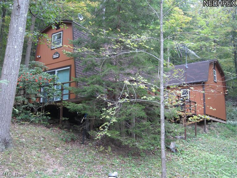 Privacy plus in this cozy cabin just minutes from Tappan Lake. Updates include a newer sliding glass door that opens to the wrap around deck. Newer roof on front side. Also includes a 24x20 framed building with 2nd floor. Windows are in and building is ready to be finished. There is also a newer 12x10 storage shed in excellent condition. Close to 3k spent to extend driveway and add new drainage lines and enlarge parking area. Most furniture stays. Appliances stay. Excludes dishes, TV and personal items. All on approx. 2 acres. Also includes parcel #29-0000445.000. Appliances not warranted. Total sqft does not reflect unfinished 24x20 building.
