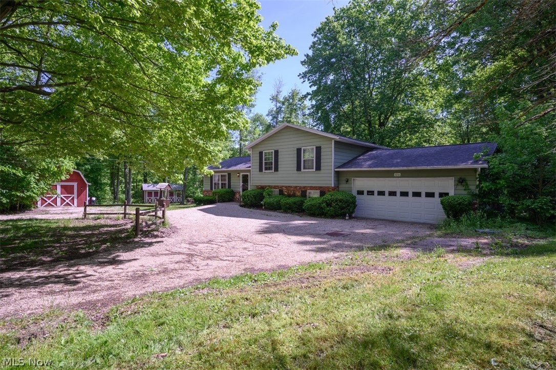 Brimfield Township! Welcome to your own private piece of paradise! This well-maintained split-level home is situated on 6.5 private sprawling and wooded acres, complete with a small pond, 2 storage sheds, 2 car attached garage, and a mini-cabin on the pond! The possibilities are endless, enjoy privacy and amazing views year round - plenty of space to spread out, host cook-outs, parties, family gatherings and bonfires! You'll fall in love with this cozy family split-level home - with a remodeled open concept main level - open kitchen/dining/living room - with a remodeled kitchen featuring maple cabinets, granite counters, subway tiled backsplash, and granite island, creating a great focal point for gatherings. Upstairs you will find three ample bedrooms and a full bath recently remodeled (tub/shower, flooring, vanity, tile/backsplash). The lower level has been finished and offers a built-in bar and another full updated bathroom w/walk-in shower. Basement (4th level) is unfinished an