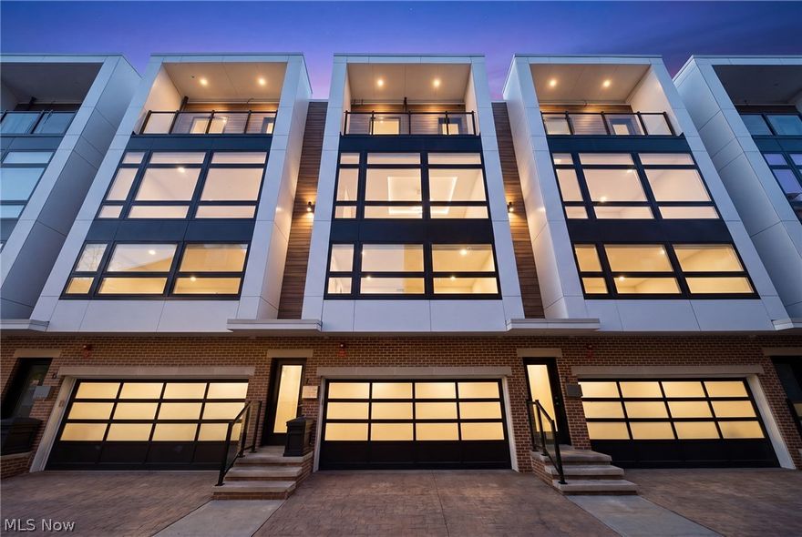 A location and townhome truly second to none! Tax abated through 2034! From the moment you step inside and ascend to the living area, you'll be captivated by a luxurious open-concept floor plan designed for everyday living and elevated entertaining. The sun-drenched living room anchors the space with a stunning stone fireplace and massive windows that bathe the room in natural light. The adjacent dining area features a built-in beverage fridge and custom cabinetry, while the well-appointed kitchen impresses with quartz countertops and premium stainless steel appliances. A convenient half bath is tucked on the stair landing for guests. Head up to the third level where brand new carpet sets the tone for the private quarters. An expansive primary suite is framed by dramatic floor-to-ceiling windows and features a generous walk-in closet and a spa-inspired ensuite bath complete with dual sinks and a beautifully tiled shower. A second full bath with a tiled tub/shower combo and quartz vanity serves the additional bedroom, which offers large windows and a walk-in closet. A dedicated laundry room with a front-loading washer/dryer combo completes this level. On the fourth level - also finished with brand new carpet - a spectacular room awaits, complete with a beverage fridge, a half bath, and access to the breezy rooftop deck. Your personal front-row seat to Cleveland's skyline, Lake Erie, summer fireworks, and the legendary Cleveland Air Show. Sunrises and sunsets have never looked so good. Back at ground level, a versatile bonus room opens to the enclosed backyard and two-car garage - a showstopper featuring a sleek polyaspartic-coated floor and impressive storage system. Step outside to the backyard, where brand new artificial turf offers a low-maintenance outdoor escape. All TVs convey! Move to an area that just keeps getting better every year (Irishtown Bend is next and new restaurants opening all the time!). The most walkable location you can dream up.