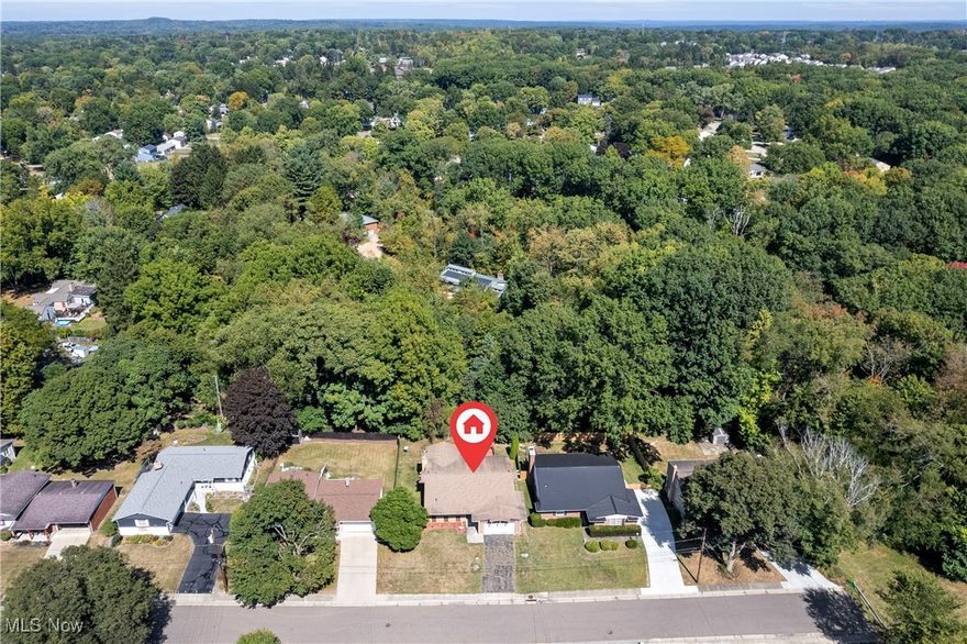 Welcome to this mid-century modern gem in the desirable Fairlawn Heights neighborhood, ideally located on the edge of Sand Run Metro Park in the heart of West Akron. This brick ranch offers 4 bedrooms, 3 full baths, and 1,682 sq. ft. of main-level living, blending timeless character with endless potential for customization. Step inside to a spacious foyer with a built-in planter that highlights the home’s unique mid-century design. A formal dining room flows into the open kitchen and expansive living room, anchored by a dramatic brick fireplace. Natural light fills the space through leaded glass windows and sliding doors that open to a private patio and deck. The backyard offers incredible potential to create your perfect retreat for entertaining or quiet outdoor living. All four bedrooms are conveniently located on the main floor. The primary suite shares a full bath with an adjoining bedroom, while the remaining two bedrooms share a second full bath. The expansive finished basement nearly doubles the living space and features another fireplace, plus a third full bath awaiting your finishing touches—ideal for a media room, recreation space, or guest suite. Additional highlights include central air, a private backyard, and proximity to highly rated public and private schools. With easy access to shopping, dining, entertainment, and both Akron and Cleveland, this home offers the perfect balance of convenience, character, and opportunity.