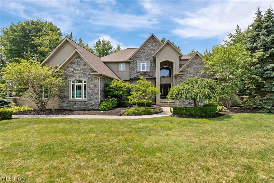 Architecturally impressive, this exquisite Solon residence is a masterpiece of quality craftsmanship & luxurious living. Nestled on .89 acres within the sought-after Solon school district, this custom built home boasts many upgrades throughout! Enter through the grand two-story foyer with a curved staircase that sets the tone for elegance. Follow the gleaming hickory hardwood floors into the formal dining room, featuring a tray ceiling. The distinctive two-story living room, complete with sweeping ceilings, a cozy fireplace, custom built-in shelving, & bar area, provides a perfect space for relaxation & entertaining. The chef’s kitchen is a culinary dream, equipped with a large center island, granite counters, custom Maple cabinetry, stainless steel appliances, dual sinks, walk-in pantry, & an eating area with patio access. Adjacent is the hearth room with a stone fireplace, creating a warm & inviting atmosphere. The main level also includes a handsome office, conveniently located laundry room, & half bathroom. The luxurious owner's suite features a seating area with mantled fireplace, walk-in closet, & an ensuite bathroom with double vanities, large soaking tub, dual toilet/bidet, separate shower, & two linen closets. Upstairs, you'll find four spacious bedrooms, each with walk-in closets & ensuite bathrooms. The lower level highlights 1600 sq ft of finished space, incl a family room, rec area, kitchenette, theater room, & half bathroom, providing ample space for leisure & entertainment. The unfinished portion offers ample storage space & is plumbed for a full bath. Outside, the expansive stamped concrete patio with a built-in grill overlooks a lush yard with a tranquil, wooded backdrop. The property includes an attached 4-car garage with an EV charging circuit/plug. This stunning home has seen many major updates incl kitchen appliances, A/C, roof, washer/dryer, furnace, & hot water tank. This property is a true gem, offering unparalleled luxury & comfort!