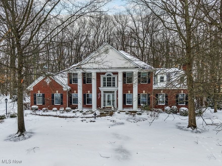 Stately brick-front colonial with a rare first-floor primary suite in desirable Woodview Estates! This former Prestige Homes model is beautifully situated on nearly an acre, offering privacy, mature trees, and generous outdoor space. Hardwood floors grace much of the main level, beginning with a dramatic two-story foyer that opens to a handsome office featuring a wood accent wall, crown molding, stained trim, gas fireplace, and custom built-ins. The formal dining room showcases elegant two-piece crown molding and is ideal for entertaining. Everyday living shines in the expansive open-concept area that includes the kitchen, eating area, family room, and sunroom. The white kitchen offers abundant cabinetry and counter space, pantry, planning desk, and eating bar. The eating area leads to the deck and private yard and flows seamlessly into the family room with cathedral ceiling and brick gas fireplace. A light-filled sunroom with walls of windows and a cathedral tray ceiling provides a peaceful retreat. The first-floor primary suite is privately tucked away and features a cathedral ceiling and spacious glamour bath with soaking tub, updated shower, double sinks, and walk-in closet—ready for your personal touch. Laundry room and half bath complete the main level. Upstairs are three spacious bedrooms, including one ensuite and two sharing a Jack-and-Jill bath. The finished lower level adds over 2,100 sq ft with a full bath, large multi-use living area, workout room, craft room, playroom, and ample storage. With over 3,700 sq ft above grade plus extensive lower-level space, this home offers room for everyone. Some cosmetic updates needed—an outstanding opportunity in a premier neighborhood. Priced reflective of updating needed and priced BELOW recent appraisal!