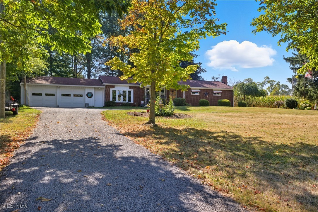 Looking for a little bit of country? This 3-bedroom, 2.5-bath brick ranch in West Branch Schools is a rural gem, set on 1 acre, with a welcoming covered porch, a convenient horseshoe driveway and vinyl windows that were updated just a year ago.
Step inside and discover a layout full of versatility. The original living room, with hardwood floors, is now being utilized as a spacious dining room, perfect for gathering around the table. The breezeway has been converted into a large living room with its own electric baseboard heat, LVT flooring, a bay window, a half bath, and sliding glass doors that open into the 3 season/sunroom, where you can relax and enjoy the views of your own slice of the countryside.
The kitchen is generously sized with an abundance of cabinetry and counter space, and the stove, refrigerator, and dishwasher all stay. Down the hall, you’ll find three bedrooms—one currently used as a closet, another for storage—and a full bath with a tub/shower combo. The finished basement is a true bonus, offering a rec room/family room with tongue-and-groove hardwood walls and a propane fireplace (the propane tank can stay). There’s also an optional 4th bedroom/office with 2 double closets and a spacious laundry area that houses another full bath (the step-in shower is being used for storage) and a hallway of storage closets. This home offers the space you need, the charm you’ll love, and the country setting you’ve been looking for. Come take a look, you might just picture yourself calling it home.