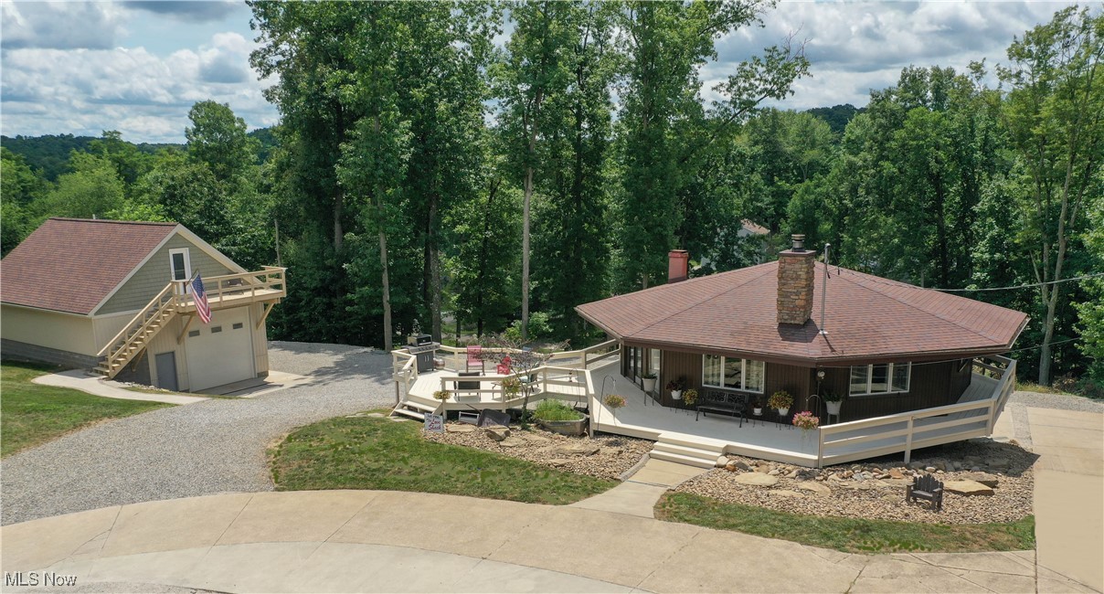 Here is a unique opportunity to own one of the original "round homes" built at Lake Mohawk. Nestled on 2.5 lots, this private setting boasts seasonal lake views. Beautifully updated, the main level features open floor plan, natural wood cathedral ceilings with beams, comfortable living room with stone fireplace, three bedrooms, full bath and nicely updated kitchen with stainless appliances. The lower level extends your living area with office space or playroom, spacious laundry area with plenty of counter space and showcases a modern second full bath. This level provides direct access to the attached garage for convenience. Home features wrap around porch with added deck...great for entertaining and cookouts or just relaxing and enjoying the views.
The property truly shines with its exceptional detached garage/workshop. Constructed in 2022, the main garage is 34' x 28', separate 200-amp service, 19' x 7' mezzanine storage area, hot/cold sink, high bay LED lighting and gas 55,000 BTU heater. Overhead door (12' x 12") with automatic opener and two man-doors for easy access. Plumbed air compressor is also available.
Large workshop upstairs with private entrance is ideal for home office or hobby room, complete with half bath and a/c unit.
Lake Mohawk has 500-acre lake for boating (unlimited horsepower), swimming, fishing, tennis court, pickleball courts, clubhouse and baseball field. Separate membership available for golf course. Convenient to Akron, Cleveland and Pittsburg areas. Auditor indicates 1 full bath, but Seller states 2 full baths.