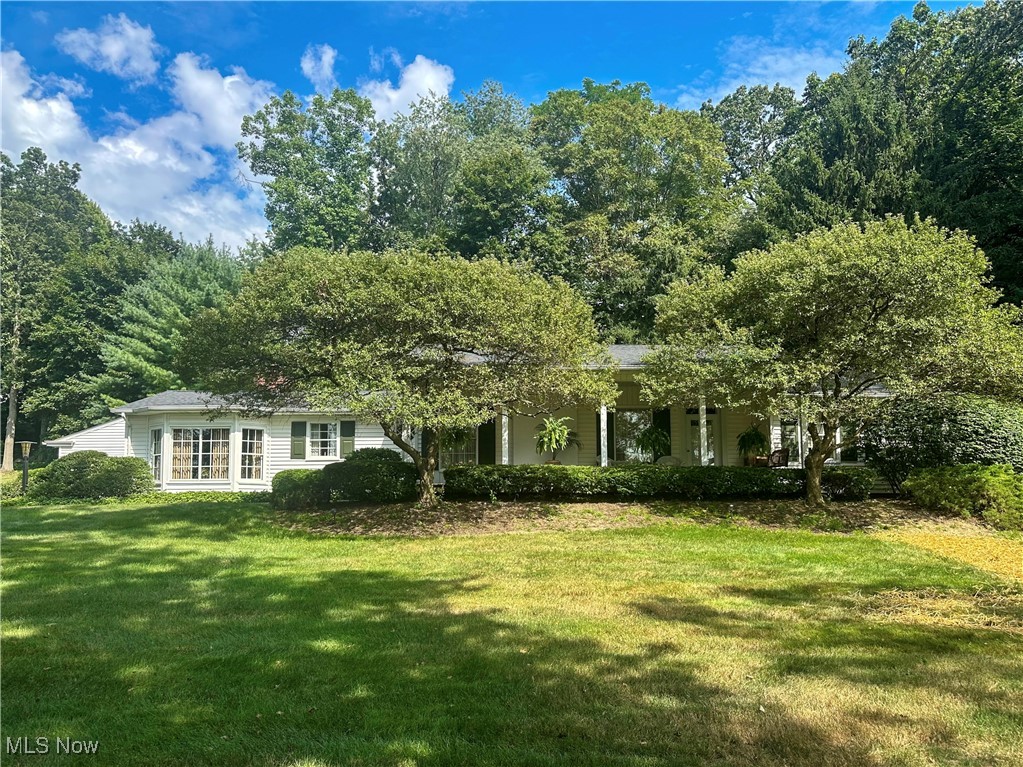 Discover the epitome of serene living in this sprawling Hunters Woods ranch home, perfectly situated on a lush 1.39-acre lot enveloped by mature trees and vibrant greenery. As you follow the long driveway, you are greeted by a charming brick walkway that leads to a covered Southern-style front porch—an idyllic retreat for relaxation and unwinding. Step inside to discover a spacious living room adorned with an elegant fireplace, a formal dining room featuring built-in cabinetry, and a large family room that boasts stunning wood flooring, a fireplace and walls of windows, offering picturesque views of the backyard. The eat-in kitchen is a culinary delight, complete with a breakfast bar, a convenient planning desk, and a charming nook for casual dining. Additional conveniences include a well-appointed laundry room and a stylish half-bath, ensuring functionality without compromising elegance. The den/study is a standout feature showcasing a beamed ceiling, built-in shelving, a third fireplace, and a stunning bay window that floods the room with natural light. Retreat to the primary suite, a true sanctuary that features a luxurious attached bathroom equipped with a jetted tub, walk-in shower, dual vanities, and two walk-in closets. Two additional bedrooms and another full bathroom complete the private quarters, providing comfort and space for loved ones and guests alike. Best of all, ample storage is found in every corner, making it easy to stay neat and organized. Step outside to discover charming brick and stone patios, perfect for entertaining or enjoying quiet moments in nature. Other highlights include a full basement, two-car detached garage, updated gas meter, and a fantastic outbuilding ideal for a workshop, potting shed, playhouse or even a man cave. This exceptional residence is located within the highly sought-after Howland school district, making it the perfect blend of luxury, comfort, and convenience.