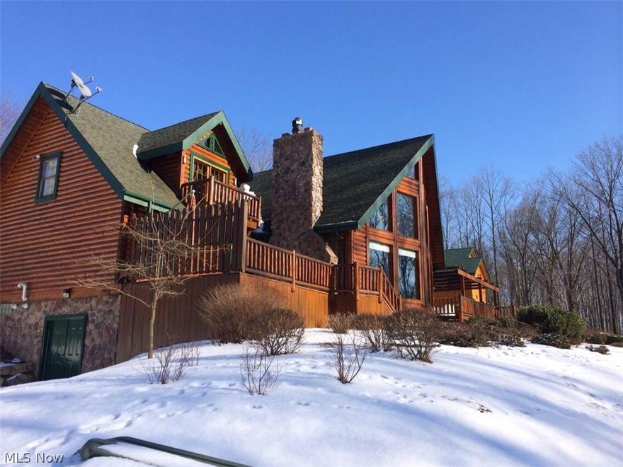 Breathtaking! Magnificent Amish built log Chalet perfectly nestled on almost 5 acres of nature's most beautiful scenery.  Let's start by driving down the winding driveway, don't worry as we are driving down the doorbell will ring letting them know we are coming!  As we approach you will feel as you are going to check into a vacation resort!  The door opens to the grande foyer leading to the great room featuring cathedral ceiling, massive 2 story stone fireplace and the entire back wall of oversized windows with the most beautiful view you have ever seen.  You will enjoy the fire looking out over the stocked lake with dock, and woods. The kitchen is perfect for entertaining.  The custom kitchen with granite table (made from trees that were cleared from the lot) and bar also features warming ovens, wine cooler and trash compactor and is open to the oversized dining room.  The master bedroom has a door leading to back deck for privacy and a master bath that could be in a magazine!  Up the