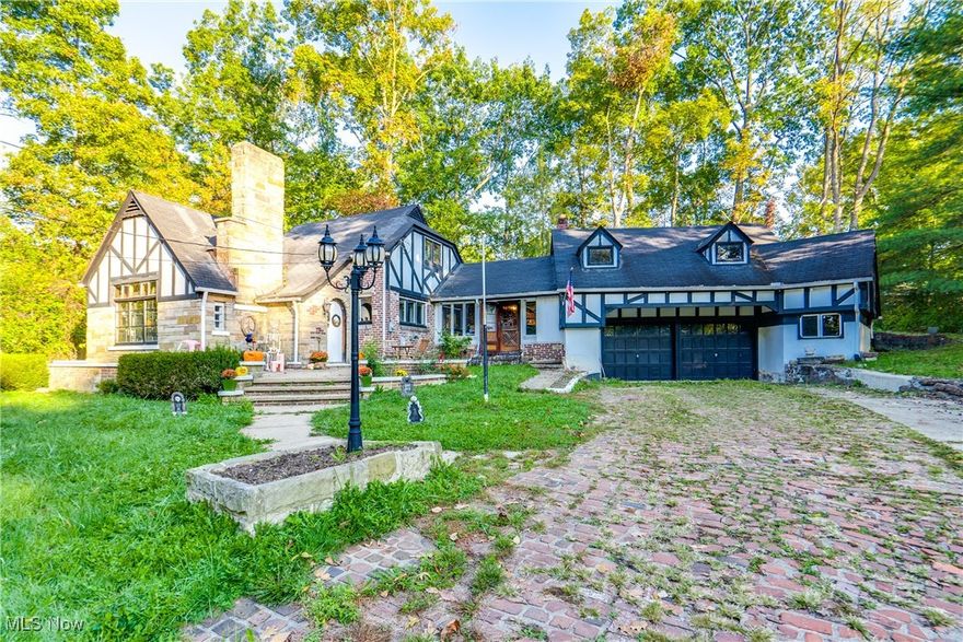 Step into this enchanting Tudor-style home, nestled in the highly sought-after Twin Hills neighborhood. Rich in history and character, this home welcomes you with a charming brick driveway and an oversized two-car garage, complete with additional attic space that’s perfect for finishing into a studio or bonus room. The captivating entryways, adorned with unique circular doors, set the tone for the home’s timeless appeal.

Inside, you’ll find beautiful original woodwork and hardwood floors, complemented by elegant windows that invite natural light into every room. The spacious living areas include a first floor bedroom and full bathroom,  warm and inviting library with coffered ceilings, built-ins, and a striking stone fireplace—perfect for cozy evenings and a family room with an additional fireplace and wood work.  The formal dining room offers the ideal space for gatherings, while the gorgeous staircase leads to 2  comfortable bedrooms and full bathroom.

Enjoy your morning coffee in the serene screened porch overlooking a beautiful wooded lot, surrounded by mature trees that provide privacy and tranquility. This home is truly a haven for those who appreciate the artistry of historic architecture and modern comforts.