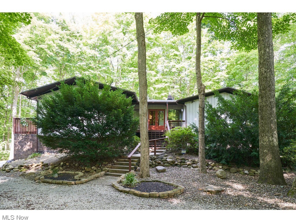 Contemporary home located on Blue bird Lake. Walk into the double front doors and to the left is a sunken living room with vaulted, planked ceilings with 2 skylights. This room flows into the dining area that also has the vaulted beam ceilings. There is a slider that leads to a deck and great treed views. The dining room over looks a 2 story great room! The kitchen is located next to the dining and living room and has cherry cabinets, a bar table and also views the 2 story Great room from above. The kitchen also has sliders that lead to a covered deck.On this level is the Master bedroom and second bedroom.The Master Bedroom ceiling is vaulted and beamed too. There are sliders off both these bedrooms that leads to small decks. The lower level is ground level from the back of the house. It offers a 2 story great room with a wood burning fireplace and nature stone flooring. The sliders lead to a screened porch that views the wooded back yard with views of Blue Bird Lake. There are 2 a