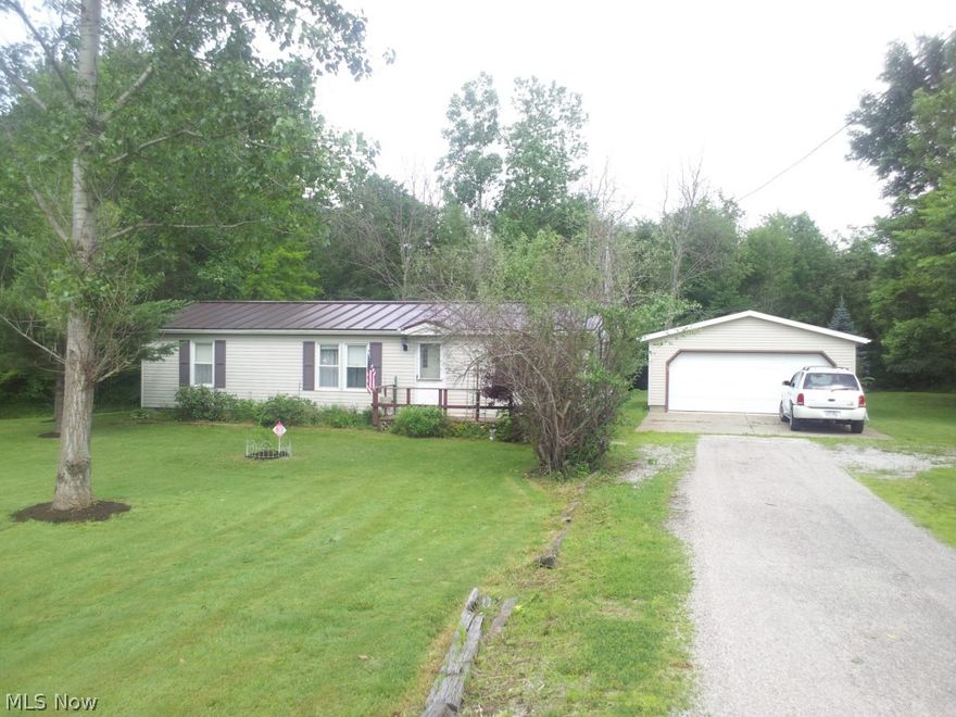 The home has a metal roof, wooded setting.