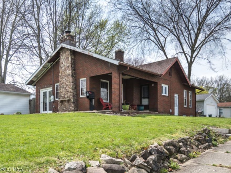 This charming Cuyahoga Falls brick bungalow is situated smack dab on a corner lot with sidewalk lined streets & mature trees. This creates an inviting feel as you approach the covered front porch. Stepping into the living room, you’ll find a wood burning brick fireplace with built in cabinets on either side. Hardwood floors run from the main living space to the dining room & on into the kitchen. Natural light pours in through the windows & the home flows easily from one room to the next. The kitchen offers just the right amount of storage & counter space for your next culinary feast. Moving on to the bedrooms, the primary room is painted a soothing blue (this color palette is used through much of the home) & offers a bonus space you could have as a sitting room, closet, workspace…it's really up to your imagination. Two other well sized bedrooms & a full bathroom complete the main level. In the basement you'll find an additional full bathroom & your laundry space. Off the back of the ho