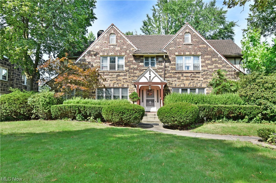 Majestic, turn of the century Tudor styling melds with remarkable, late Victorian flavor to bring three floors of finished living space within this six-bedroom Youngstown estate! Set in a historic district, the stone-faced home nestles beneath lush foliage as a bold red patio rises from the landscaping to present the impressive grand foyer. The living room immediately catches your eye as lattice windows spill sunshine across the hardwood flooring and marbled fireplace. Sculpted crown work continues into the rear parlor where a second fireplace is found. The main hall offers a lovely half bath, while bridging the decadent formal dining room with French door partitions. An expansive kitchen shows off brass tile work as a generous casual dining space enjoys window lined views. First floor laundry is located within the cabinet lined pantry room. At the second-floor landings, built in cabinets join a full bath while the expansive master suite opens to reveal a large walk-in closet and its o