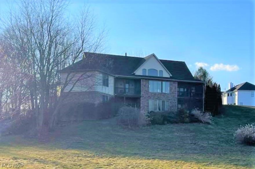 Welcome to 3075 Sunnybrook Road in Mogadore! This incredible 5,500 square-foot raised ranch home sits on 3 acres and has 4 bedrooms, 5 bathrooms, an indoor hot tub room, and 4 porches. Step inside the front door to the entrance/living room with breath-taking Cathedral ceilings, a stone fireplace, and picture windows with a lake view. The kitchen and dining room have a Cathedral ceiling with recessed lighting and skylights. Oak cabinets surround the kitchen, giving you plenty of storage space. One of the screened porches is located off the dining room. The main level also has a mudroom with laundry hook-up, 2 bedrooms, and 3 bathrooms. The master suite has a spacious bedroom, access to a second screened porch, and a huge bathroom that has a soaking tub, walk-in closet, and dual sinks. The lower level is made up of a huge living area with large windows, as well as 2 bedrooms and 2 bathrooms. Two additional porches are located on the lower level (one screened, one open). A bedroom in the