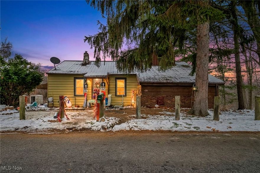 Welcome to a charming ranch-style home tucked among mature trees on a quiet Akron street. Inside, a spacious living room with vaulted ceilings, exposed beams, and a stone fireplace sets a cozy, rustic tone. Large windows bring in soft natural light, giving the room an inviting, open feel. The adjoining kitchen offers abundant cabinet storage, warm wood tones, and plenty of prep space with a central island—ready for everyday use or future customization.

Three comfortable bedrooms sit on the main level, each with its own character and natural light, and the home includes two full baths—one on the main floor and another in the lower level. A full basement provides additional storage, laundry space, and flexible areas for projects or hobbies.

Outside, the property features a deck overlooking a tree-lined backdrop, creating a peaceful place to unwind. A carport, unpaved drive, and an outbuilding add everyday convenience. With its appealing layout, generous living room, and a setting surrounded by woods, this home offers a great opportunity for those looking to personalize a space of their own or for investors seeking their next project.
