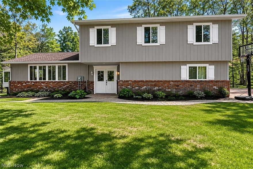 Tucked away on a peaceful cul-de-sac in Chesterland, this beautifully updated and meticulously maintained 4-bed, 2.5-bath split-level offers the perfect blend of comfort, privacy, and everyday functionality on an incredible 3.6 acre corner lot. This move-in ready home is surrounded by lush greenery, mature trees, and scenic backyard views in every season. Step inside to discover a bright and welcoming layout featuring neutral décor, durable vinyl flooring throughout, and a seamless flow from the front foyer into the spacious living and dining rooms with soaring vault ceilings. The fully updated eat-in kitchen is complete with quartz countertops, stainless steel appliances, and easy access to the cozy family room featuring a wood-burning fireplace and two sliding doors overlooking the backyard oasis. A third sliding door off the dining room leads to the deck and patio, ideal for entertaining or enjoying the outdoors. One true highlight of this home is the incredible four-season sunroom addition, a stunning glass-surrounded retreat with panoramic wooded views that create the perfect place to relax year-round. Upstairs, the large primary suite offers a walk-in closet and private bath with remodeled shower stall, while three additional generously sized bedrooms provide plenty of space for family, guests, or home office needs. Additional features and updates include: Upstairs full bath remodel ('25), Main-floor laundry room with updated half bath, Full basement with rec room and interior waterproofing ('14), New septic system ('15), Tear-off roof replacement ('12), Hot water tank ('18), Zoned heating and A/C, Many newer windows and two newer sliding doors, Exterior painted ('22). The picturesque backyard also features an adorable wooden bridge with new lumber leading to the shed, adding even more charm to this serene property. Pristine and thoughtfully updated, this exceptional home offers the rare opportunity to enjoy privacy, nature, and modern living all in one.