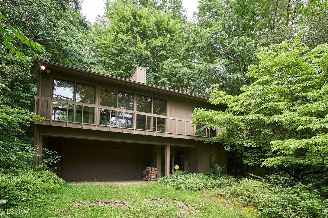 This stunning 3BR 3BA raised-ranch berm home in Copley Township is a single-owner, custom-built masterpiece, offering a perfect blend of architectural innovation and modern comforts. Designed to harmonize with its surroundings, the home is built into bedrock, combining passive solar architecture with floor-to-ceiling windows that flood the space with natural light and provide breathtaking views of the wooded 18.21-acre property. Inside, the 3,180 sq ft are complemented by an add’l two-story “air space” that enhances energy efficiency and provides functional living space year around. The second floor, or main living level, features vaulted ceilings, living room w/ wood burning fireplace, updated galley kitchen w/ stainless steel appliances and granite counters, dining room w/ built-in shelving, laundry/utility room, master suite w/ full bath, WIC, and private deck, add’l guest bedroom and full bath. A separate in-law suite on the 1st floor offers a private retreat, complete with a kitchenette, living room, bedroom, and full bath, offering both comfort and independence for extended family or guests. The home also features a 2-car attached garage; rear deck & two floor to ceiling frieze murals custom commissioned by a local artist & legend. Step outside to explore your own wooded escape, complete with mature trees, glacial boulders, rock formations, and enchanting waterfalls. These natural elements create a serene, private oasis perfect for hiking, nature walks, or simply enjoying the peaceful sounds of flowing water. Surrounded by serene, snow-draped trees in winter and lush greenery in warmer months, this home offers unmatched privacy and tranquility, making it the ultimate wooded retreat for those seeking a deep connection to nature. Whether you're drawn to sustainable design, unique architecture, or the peaceful seclusion of wooded acreage, this home is a rare find. Schedule your private showing today!