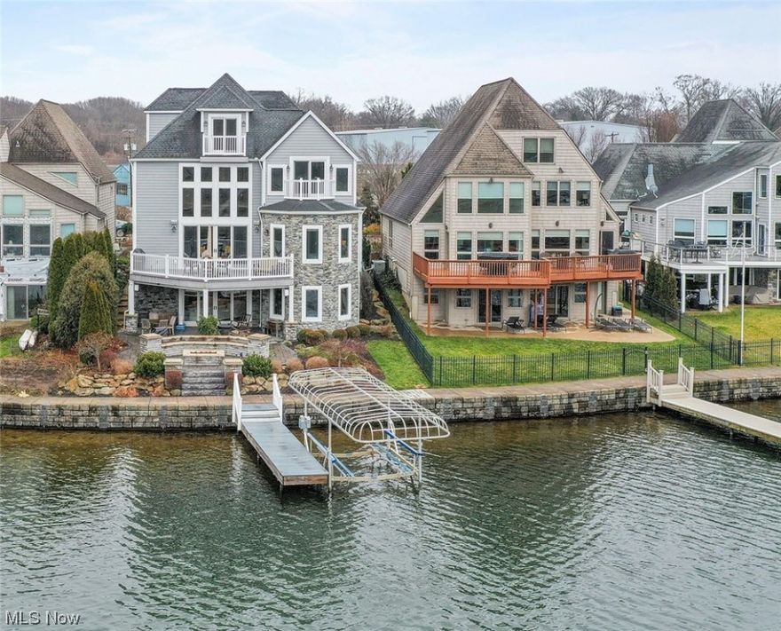 One of the most desirable 4-story 2015 custom-built homes on Portage Lakes East Reservoir, w/over 4,742 living sq ft including beautifully appointed finished walkout basement, a private boat dock, boat lift, heated 3-car garage w/ a car lift for a 4th car, in the desirable Heron Watch community featuring a boardwalk, and located in Green School District. The Portage Lakes consists of multiple lakes connected through channels, and is great for fishing and a variety of other recreational activities year round. This home features solid hickory hardwood flooring, solid core doors, private balcony on all levels of the home looking out to the lake, two tier patio with outdoor firepit with a 1-inch gas line, Sonos built-in speakers, and water heated flooring in the lower level and the garage, keeping home utility costs low. The chef's inspired eat-in kitchen incudes top of line built-in appliances, including Electrolux refrigerator, walk-in pantry, and high-end finishes. The owners' suite has direct views of the lake, access to the deck, 2 walk-in closets, & an en-suite glamour bath. There are 2 laundry rooms on different levels and convenient laundry shoot. There is a "secret" bonus room on the third floor w/ hidden access behind bookshelves along w/ a finished game room on the fourth floor. Since building the home, owners have spent over $180,000 in additional updates. Some of the updates include: landscape and hardscape, added second laundry room on lower level, installed whole house surge protection, installed custom power operated sun shades, outlet for generator, dock lift, car lift, and so much more. Conveniently located near I-77, I-277, shopping, restaurants, parks, & many other local attractions. INCLUDED are both kitchen appliances , boat lift, hydraulic car lift, work bench in garage, TV mounts, window treatments, & portable generator. The HOA fee also includes snow plowing of the community streets, private driveway, as well as maintaining the seawall.
