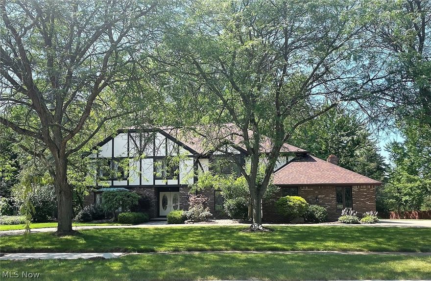 Spacious 4-bedroom 5-bath Tudor home. Let the beauty of this home unfold as you enter the Foyer, hardwood floors & crown molding welcome you.  The Kitchen boasts granite counter tops & stainless steel appliances and opens up nicely to a step down Family Room complete w/fireplace, perfect to visit family & friends. As you look out the rear of the home, it has the feel of your own nature retreat as the wooded lot drops down to a small ravine and a quaint stream. You'll never believe that you're in town on this over 1-acre double lot.  Enclosed porch on the back of the home to enjoy the outdoors bug-free and a large deck and patio. The 2158 SF finished basement is the ultimate man cave, complete with full bar and yet another fireplace, perfect for adults and kids alike. It even has a dance floor, workshop and other storage rooms.  Don't miss the opportunity to own your own personal retreat.