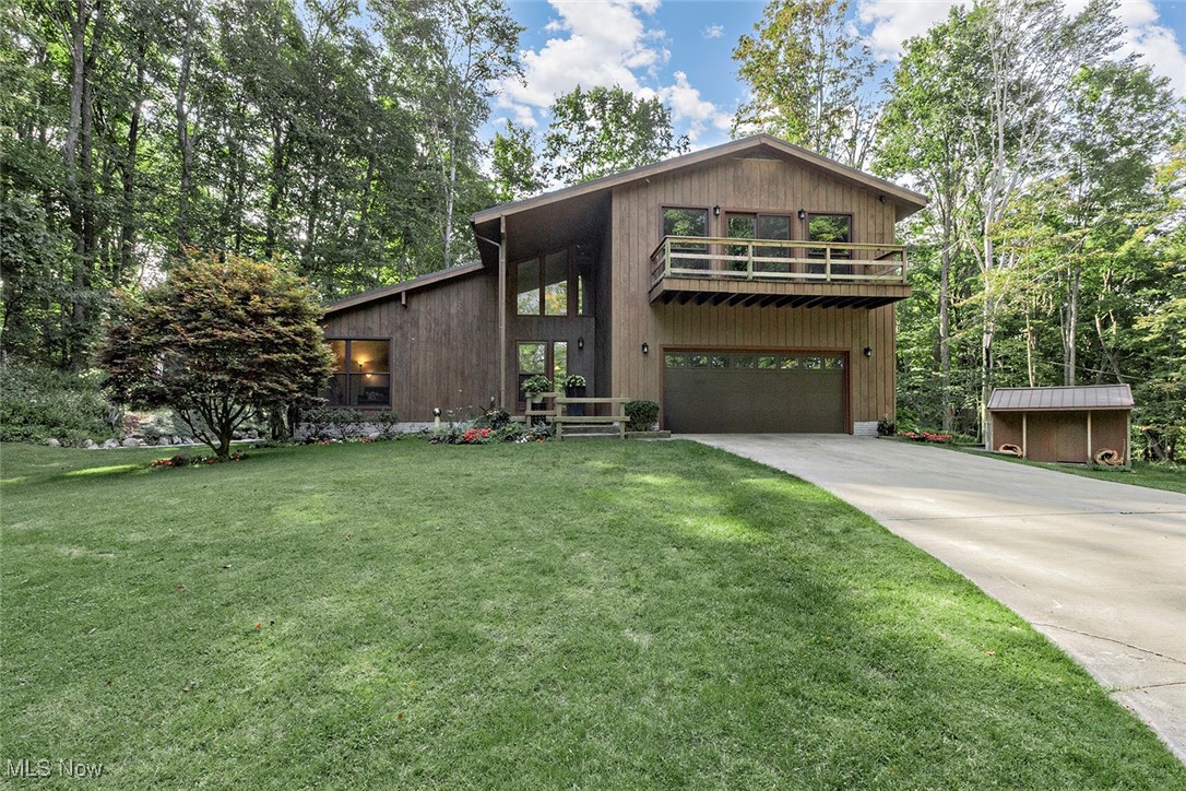 Experience the perfect blend of modern comfort and natural beauty in this 4-bedroom, 2.5-bath split-level home, set on 6.55 acres in Chesterland. This 3,381-square-foot home is designed for both everyday living and peaceful relaxation. A warm wood entryway leads to a light-filled living room with a beamed ceiling and a formal dining room featuring rich wood floors and floor-to-ceiling windows. The spacious eat-in kitchen boasts walnut-toned cabinetry and generous counter space, perfect for any home chef.
The home's layout is both practical and inviting. A cozy family room with a striking brick fireplace flows into an expansive sunroom with a built-in hot tub. The upstairs primary suite offers a private balcony and a spacious bathroom with a dual vanity, while three additional bedrooms provide ample space. Downstairs, a finished basement with Nature Stone flooring and a full bathroom can serve as a versatile rec room, studio, or office. Step outside to a large deck with built-in seating and a stone fireplace, creating an ideal space for outdoor gatherings. With a two-car garage, a paved circular driveway, and a detached shed, this home provides both charm and functionality in a serene setting close to modern amenities.