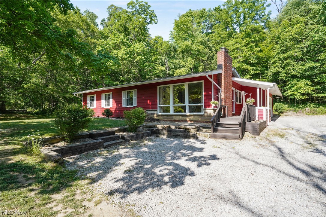 A postcard setting! Welcome to this beautiful three-bedroom, two full bath ranch home situated on 1.64 wooded acres. There is a large covered front porch which is great for welcoming family and guests. The inviting open living room offers wood floors, a brick fireplace with mantle, large wall of windows to let the natural sunlight through and is open to the dining room and kitchen. The bright kitchen has a new gas stove and dishwasher (2022), refrigerator, plenty of cabinets, and a backdoor that leads to the recently updated deck where you can sit out and enjoy that morning cup of coffee or look at the fabulous, wooded views. Master suite has wood floors, a full walk-in closet, and a beautiful, full bathroom with tiled/glass shower, heated ceramic floor and vanity. There are two more bedrooms with wood flooring and another bright, full bathroom that finishes the first floor. Natural woodwork throughout the home. The lower level offers finished area for a family room with gas fireplace,