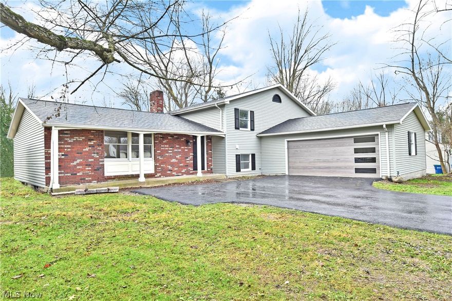 With its expansive, four-bedroom layout and desirable Howland location, this freshly remodeled split level easily stands out from the crowd! First impressions will quickly notice its stylish, custom garage door and brick façade that waits under the covered front patio. Behind, a wooden deck overlooks the back yard. Step inside to be met by an impressive living room that opens to reveal tall ceilings and warm, hardwood style flooring. Formal dining enjoys bespoke lighting and sliding doors for natural light and scenic views. The central kitchen employs gorgeous brickwork paired with dark stained cabinets and modern stainless appliances. Upstairs, an inviting full bath joins the carpeted bedrooms that line the hall. An oversized master suite brings spacious appointments to include a personal vanity, walk-in closet and gorgeous full private bath. At the lower level, a long running family room takes advantage of the fireplace inset mantle. A bonus room breaks away for easy rec space and en