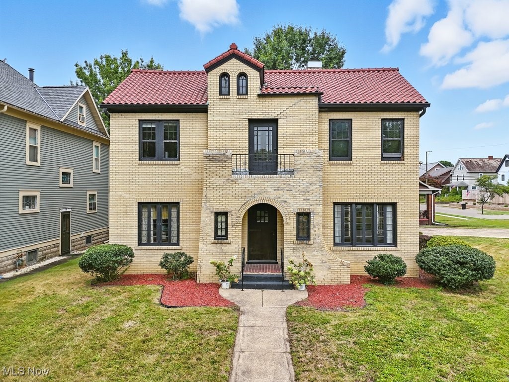 Stately brick Spanish Revival colonial situated on a picturesque corner lot in the heart of New Philadelphia - recently named one of "The 10 Safest And Most Peaceful Places To Live In Ohio". In a quiet neighborhood and walking distance from historical downtown, this classic Mediterranean-style home, with its statement clay-tile roof, perfectly melds peace and convenience, updates and preserved charm. Take a step into the foyer, complete with a mail/coatroom, where you'll instantly be wowed by the striking crown molding, gleaming dark hardwood floors, and the elegant staircase. To your right is the enchanting living room, with abundant windows and French doors leading to the covered side porch with sweeping archways and views of the lush yard. The main level also provides a formal dining room, the large kitchen, a powder room, and the cozy study with ornate leaded glass door built-ins and a lovely tile fireplace (gas). Upstairs, an open hall leads you to the sprawling Primary Bedroom with a WIC and attached office/dressing room featuring the adorable Juliet balcony perched over the front yard. Two additional spacious bedrooms and the updated full bath with a tub and a walk-in shower round out the upper level. Ample storage space awaits in the walk-up attic, full basement, and new detached 2-car garage. Several recent updates include: new AC (2024), interior paint, updated plumbing & electrical, and new water & sewer lines to the street. Don't miss your chance to make this iconic property your own!