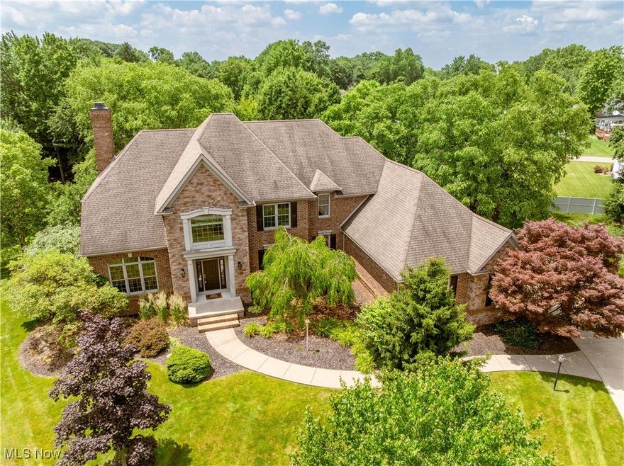 Stately brick & stone colonial situated on a quiet, tree-lined cul-de-sac in the esteemed St. James Place subdivision of Lake Township. Enter into the welcoming foyer which connects to a living room on the left (currently used as a play room), office/library on the right, and continues on to the sprawling eat-in kitchen with an island, breakfast bar, SS appliances, a walk-in pantry, granite counters, and ample cabinet space. Adjacent to the kitchen is the breathtaking Great Room, adorned with cherry built-ins, a stone fireplace (gas), a princess balcony, and a magnificent wall of windows, offering serene views of the multi-tier deck and lush back yard. Tucked behind the kitchen and connecting to the dining area is the cozy den, with its own gas fireplace. The main level is rounded out by a powder room, laundry, and the Primary Suite with his & her closets and the large bath with a jetted garden tub, walk-in shower, and separate vanities adjoined by a dressing table. Upstairs are 3 additional spacious bedrooms, 1 with an ensuite bath and the others with a Jack & Jill bath. The extensive walk-out lower level offers over 1,500 square feet of additional finished living space, with a game room, sitting room, dining area + bar w/seating, workout room, and tons of space for storage. Attached, side-facing 3-car garage & oversized driveway. Newer HVAC, water softener & tankless water heater all within the last 5 years. You will be wowed by the quality of construction - featuring stunning original woodwork, crown moulding, built-ins, and gleaming hardwood floors - schedule your showing today!