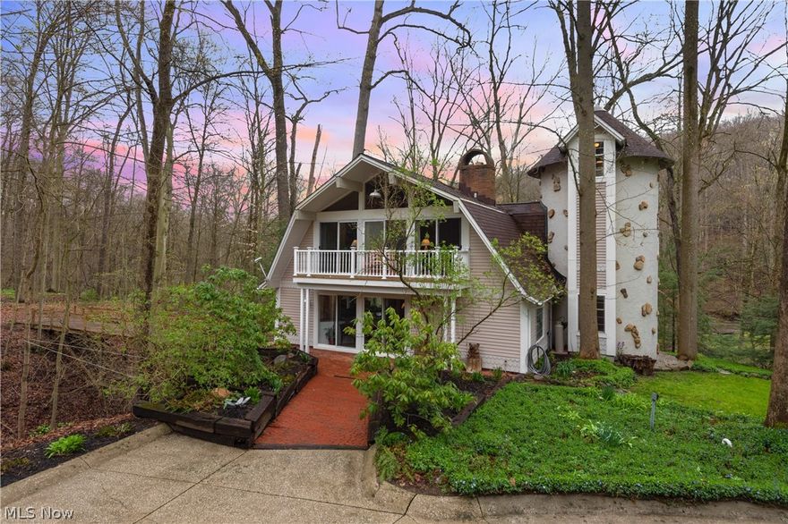 A long winding driveway welcomes you to this charming riverfront Dutch colonial revival that feels completely serene & secluded while still being located on the banks of Chagrin Falls. The 3 acre property is perched riverfront which allows for constant calming white noise. The home itself is framed by deck walkways to explore the surrounding nature. Inside the main house you will find soaring vaulted ceilings with solid wood beams, thin plank blonde hardwood floors, picture frame windows, seamless indoor/outdoor flow with endless sliding doors, custom wood staircase railing, and great room with all brick fireplace w/wood burning iron stove. Entertain from the cook’s kitchen that is equipped with large center island, double ovens, white cabinetry, and glass tile backsplash. You will also find a unique pub style bar! The lofty master suite is incredibly open & airy, has a gas fireplace of its own, and an attached circular master bath. The 5 car garage has a finished and heated second flo