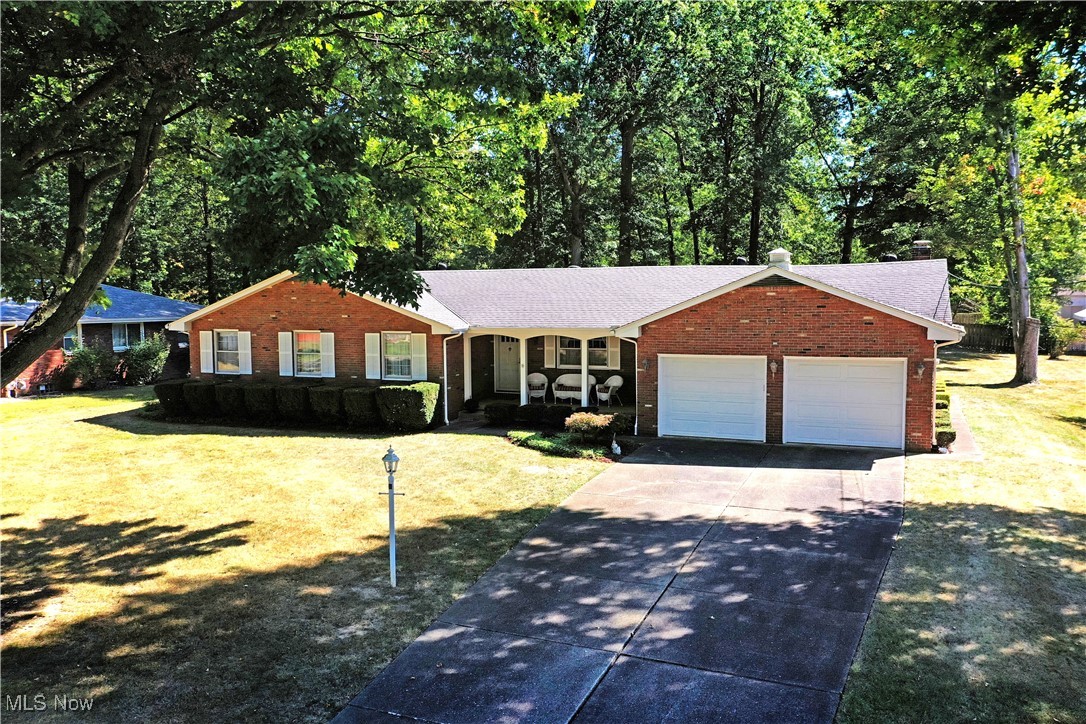 What are you waiting for? This expansive one owner Boardman ranch has everything you’ve been looking for and more! Offering up its highly desirable, all-brick construction the home doubles down with a fantastic location set within a bespoke neighborhood just minutes away from scenic parks, shopping and dining locations alike. The quiet lot is marked by tall trees that create a park-like setting as the cement driveway leads up towards the attached two car garage and covered front patio. Inside, the tiled foyer branches into both a formal dining room and main hallway before extending out to find a remarkable kitchen with its own shared casual dining space. An elegant backsplash runs between the custom cabinets and wrapping stone countertops that provide additional bar top seating. A short hall transcends a colorfully tiled half bath before finding a remarkable family room with hardwood flooring and a towering brick mantle with inset fireplace. Nearby, a finished sunroom brings window lined surrounding for easy entertaining with a view. Opposite the foyer, the main hallway finds three substantial bedrooms, each with hard wood flooring and ample closet space. An equally impressive full bath joins them at mid hall with its bright and inviting colorways. Downstairs, The oversized laundry room finds a second full bath while a workshop area offsets the incredible lower rec space complete with a full corner bar.