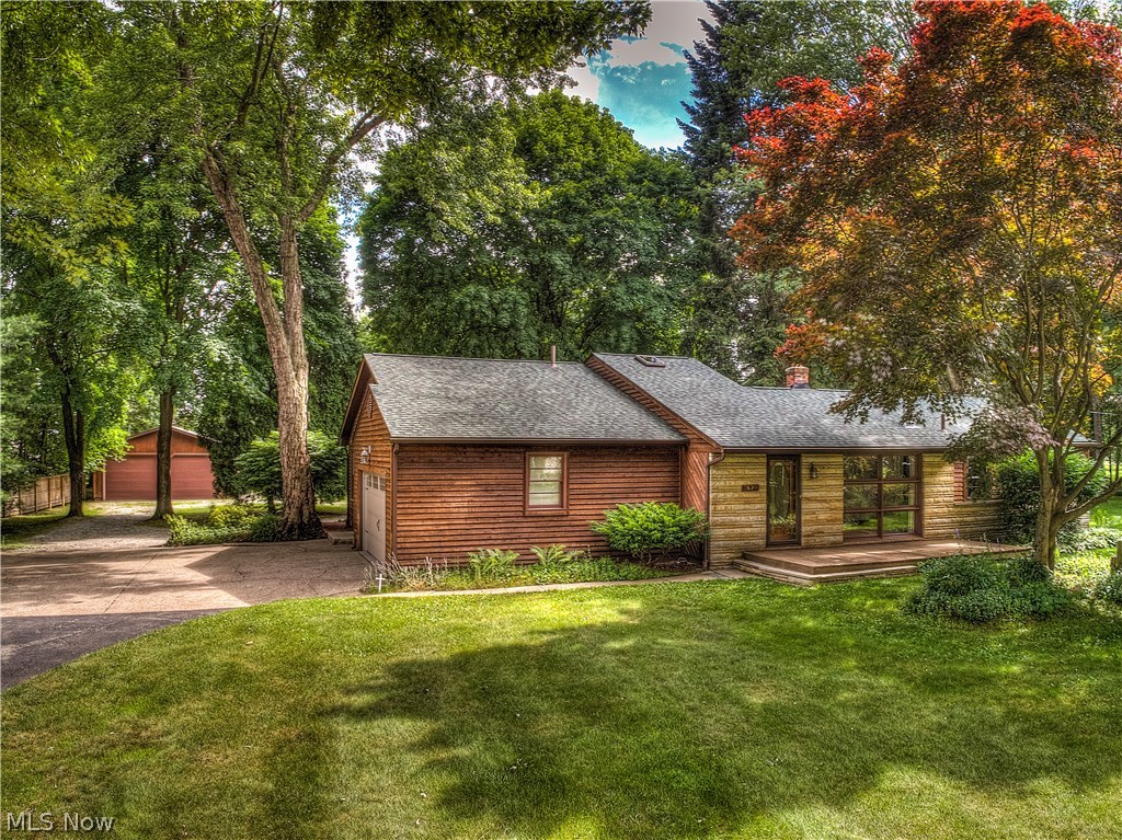 Beautiful tranquil setting on 1.7 acres with lake privileges in the City of Green/Portage Lakes area is this charming well built cedar & stone ranch* Open & spacious offering 3 bedrooms/2 baths, 1608SF plus an additional 350SF in partially finished basement with 2 car attached & 4 car detached garage* Hardwood floor throughout starting with the entrance with beveled glass door, side lights & transom window* Vaulted great room with wood burning stove, wide plank wood floor & atrium door to 1300SF deck with lighting* Living room with wood burning stove & wood floor* First floor with 2 full updated bathrooms- one with granite, walk in shower with 3 shower heads & tile floor* Spacious eat in kitchen with island, bay window, retro stove & ample cupboard space* 3 bedrooms with wood floors* 1st floor laundry with wood floor & includes dryer* Partially finished recreation room with new carpet, bar & retro refrig* Glass block basement windows* Plenty of basement storage or workshop area* Centra