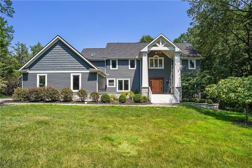 Welcome to your private estate nestled on a rare 6-acre wooded lot in Hudson! This stunning colonial offers over 4,400 sq ft of finished living space, blending timeless design with modern comfort. A welcoming front porch invites you in through a dramatic two-story foyer with a split staircase. The main level features a natural flow between the formal living room and dining room, where a wall of windows offers breathtaking views of the wooded property. The bright white kitchen boasts granite countertops, stainless steel appliances, and an island with seating for three. An eat-in area connects seamlessly to the spacious family room, creating an open-concept layout perfect for everyday living and entertaining. The family room is a showstopper with its white fireplace, vaulted ceiling with wood beams, and a stunning wall of windows that fills the space with natural light. Also on the first floor: a dedicated office, a powder room, and a finished laundry/mudroom with custom-built lockers and extra storage, located just off the attached 3-car garage. Upstairs, the primary suite features a large walk-in closet and a spa-like ensuite bath with a luxury walk-in shower. Three additional bedrooms and a full hall bath complete the second floor. The finished lower level offers over 1,200 sq ft of additional living space, including a custom-built bar made from reclaimed barn beams—ideal for entertaining or relaxing.
Step outside to enjoy a two-tiered back deck overlooking your private backyard oasis. A newly built outbuilding provides space for up to 4 additional vehicles or a dream workshop. It features a cedar plank ceiling, a loft, and is plumbed for water and gas. Nearby, you’ll find a greenhouse and chicken coop for added outdoor charm.