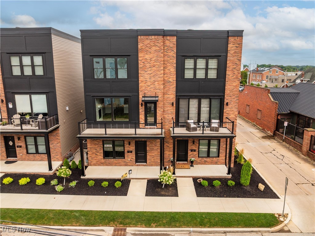 Luxury. Location. Lifestyle- Experience refined urban living in this one-of-a-kind luxury townhome located in the heart of downtown Wooster—steps from fine dining, banking, and entertainment. Every inch of this 2-bedroom, 2.5-bath home has been thoughtfully designed with upscale living in mind. Inside, you’re greeted with soaring 9-foot ceilings, oversized custom trim, rich flooring, and elegant custom paint. Designer lighting and custom hardware throughout the home—on doors, cabinets, and even the appliances—elevate every space. Remote-control blinds provide modern convenience. The open-concept main level is a showstopper. The gourmet kitchen features quartz countertops, a walk-in pantry, a farmhouse sink, and top-of-the-line Café stainless steel appliances—including a stylish range with a premium vent hood and 6 burners range. A dedicated coffee/tea bar and planning desk add functionality, while the large dinette flows perfectly into the dramatic great room with exposed brick, a cozy fireplace, and a true city-loft vibe. Enjoy not one but two balconies, perfect for entertaining or relaxing. The lower level has been transformed into a stylish bourbon/media room complete with built-in cabinetry and a custom mudroom area for coats and shoes—offering flexible space for your lifestyle. Upstairs, the luxurious primary suite includes two custom walk-in closets and a spa-like bath with dual vanities and quartz counters. The second bedroom offers its own ensuite bathroom—ideal for guests. Laundry is conveniently located on the upper level. The attached 2-car heated garage includes hot and cold water, perfect for year-round convenience. HOA includes snow removal, landscaping, and exterior maintenance. Easy access to Route 30. This is not your average home—it’s a rare, luxurious retreat in a walkable downtown setting. Bonus- Excellent parking for guests and the home is sold fully furnished with luxury Arhaus furniture.