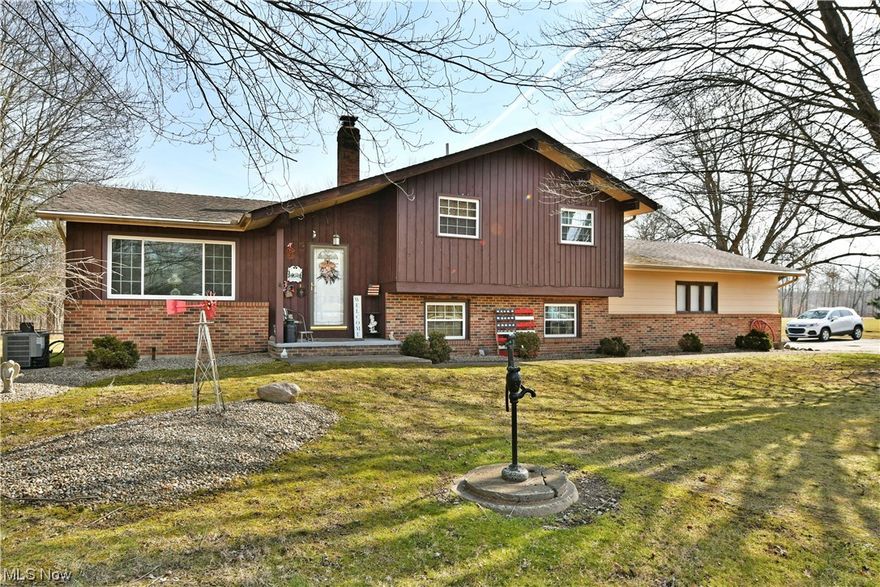 This wonderful three-bedroom split level home places you in a scenic, semi-rural setting as you take in the natural privacy and  pond from the fantastic rear deck! Sat far off the road, the residence quickly captivates with its mix of warm brick work and accenting chocolate colored siding that highlights the covered front patio. An attached three car garage features a third bay for easy equipment storage or converted workshop space.  A tiled foyer brings you inside to find a carpeted living room with plenty of natural light thanks to an oversized picture window. High, sloping ceilings continue into the central dining room where an exposed truss joins hanging light. The patio entry allows for even more sunlight as you enjoy your meals. Looking downward, a wrought iron gate runs along the open lower wall to reveal the large family room below with a fireplace which includes a convenient insert. Across from formal dining, a robust kitchen showcases a galley layout with an island dividing a second eat-in dining space. Up the carpeted stairs, a full bath accompanies a trio of bright and inviting bedrooms to include the larger master. Warm yourself by the family room fireplace below as stylish woodwork trims the walls. The second full bath is located outside of the lower floor laundry with its hidden corner shower. An additional basement allots for continued storage solutions. Most windows have been replaced in 200, the furnace and air were new in 2016, electric was updated in 2005.