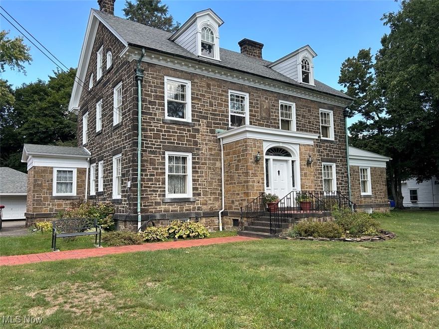 Beautiful Stone Century Home with Updates and Garage On 1.15 Acres - 5 Bedrooms, 4 Full Baths, Two Half Baths, and Finished Basement - Loads of Character - Built In 1890 By Vodrey Family. Online Bidding Available On Real Estate. ABSOLUTE AUCTION, all sells to the highest bidder on location. ONLINE BIDDING BEGINS MONDAY, OCTOBER 14, 2024 – 5:30 PM and AUCTION LIVE ON-SITE BIDDING WILL BEGIN THURSDAY, OCTOBER 17, 2024, 5:30 PM, RE SELLS FIRST. 3-story stone home features an updated kitchen with granite countertops, tile floors, modern appliances, a double oven, and an island with a cooktop and overhead range hood as well as a butler’s pantry. Server staircase to the second level from the kitchen. Pantry area with lots of storage and a separate entryway into the house as well as a half bath. Dining room with wall-to-wall built-ins, large triple bay windows, and beautiful floor-to-ceiling woodwork. Wonderful 17x19 screened-in back porch with tall plank and beam ceilings. Stunning front entryway with tile floors and arched leaded glass doorways into the foyer. Off the main foyer is a library/den with a fireplace and built-in bookshelves as well as a living area with wood beam ceilings, a large fireplace, beautiful built-in bookshelves, and large windows. Hardwood floors throughout the main level. Grand staircase to the second level which offers a large master suite with cedar-lined closets, built-in shelving, and tile bath. The second level also has an additional bedroom with a private full bath, a third bedroom, laundry, and an office. The third level fully finished with tall ceilings offers 2 more bedrooms with cedar closets and 2 more full baths. Finished basement with LVP flooring, double-sided fireplace, and built-in bar w/ fridge and sink as well as a half bath. Gas boiler heat, walkout stairs from the basement. Detached 25x32 stone 2-car garage with overhead doors, blacktop drive. The home sits nicely on 1.15 acres and is meticulously maintained and move-in ready.
