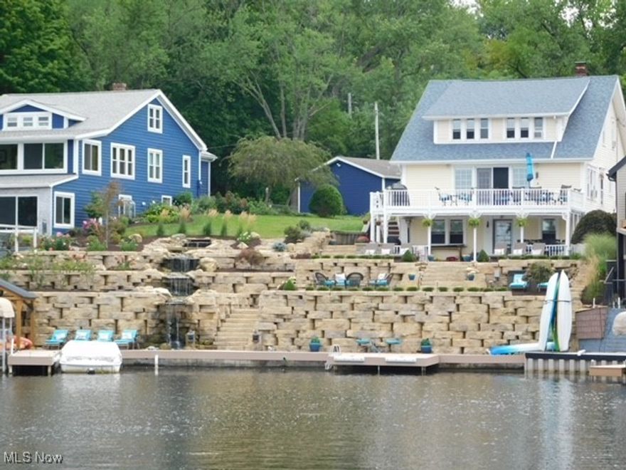 An entertainer's DREAM! Nestled on the shores of East Reservoir on the main chain of Portage Lakes sits this majestic 3 level home with 95 ft of lake frontage with views of the iconic Portage Lakes clock tower.  A mix of old charm with built-ins and stained glass coupled with modern updates; truly a one of a kind treasure. 2 car garage plus parking for 8 cars! PUBLIC water and sewer. 5 bedrooms (with additional flex room used as a 6th bedroom in lower level), 4 full baths, 3 full kitchens; including a top level in-law or junior suite. Walkout lower level features a kitchen for entertaining guests lakeside, 6th bedroom, full bath, and large recreation room with heated floors. Main level features living room with views of the lake and French doors to the deck, 2 full baths, 2 bedrooms, updated kitchen with granite countertops, plus Master bedroom suite with double closets and updated master bath and tiled shower. The seller has made extensive updates - including a massive landscaping update with waterfall, exterior lighting, 2 new docks and lift. Recognized on the cover of a publication of the Ohio Landscape Association magazine, the exterior luxury lakeside stonework lined with perennial flower beds features gorgeous multi-level entertaining spaces with firepit, hot tub, covered gazebo, and outdoor grill. Additional updates include public water, a new roof, updated main level kitchen with beautiful granite counters and backsplash, and basement. Turn up the charm, fire up your pontoon, call your friends, and stay awhile. Make this one yours and start living your dream on the beautiful Portage Lakes!