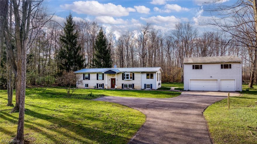 Welcome to 9540 Taylor May Rd, a 5.19-acre retreat in Bainbridge Township, minutes from downtown Chagrin Falls. The 2,976 sq ft main home features 5 bedrooms and 2 baths. An open-concept kitchen and dining area flows into a sunlit side addition, ideal for a home office or playroom. The lower level includes additional bedrooms and a sump pump. Outside, a deck overlooks a wooded, low-maintenance backyard. The heated 3-car garage features dedicated workshop space. Just above it is a major property highlight: a 728 sq ft finished bonus suite. Featuring a private entrance and a full bathroom, this flexible space is perfect for guest quarters, a home office, or a professional studio. The expansive 5+ acre lot offers ample space for hobby farming, gardening, or future outbuildings.