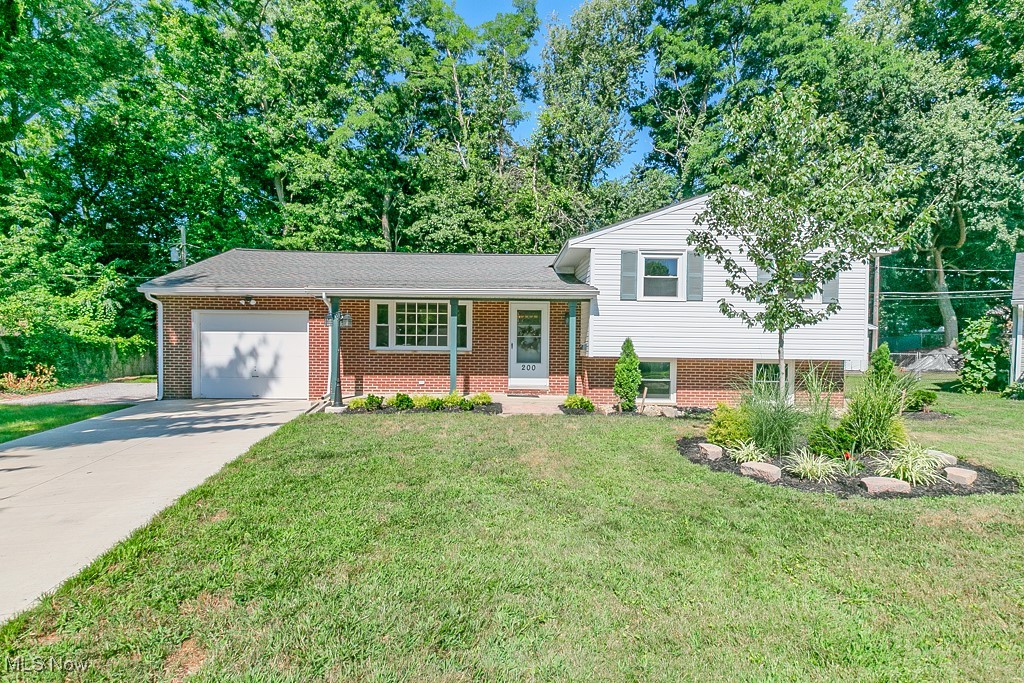 Welcome to 200 Tiber Drive — a beautifully updated and move-in-ready three-bedroom split-level home tucked away on a quiet cul-de-sac in Painesville. Situated on a thoughtfully landscaped lot, this 1,500-square-foot residence offers a perfect blend of charm, comfort, and modern convenience. A brand-new concrete driveway and sidewalk apron welcome you to a covered front porch, setting the tone for the care and quality throughout. Step inside to a ceramic-tiled foyer that opens into a spacious living room with gleaming natural hardwood floors, which continue into the adjoining dining area, creating a seamless flow for both daily living and entertaining. The centrally located kitchen features updated laminate plank flooring and connects directly to a rear family room filled with natural light, with a sliding glass door that opens to a private, tree-lined backyard and patio — ideal for quiet relaxation or outdoor gatherings. Upstairs, you’ll find three comfortable bedrooms and a stylishly updated full bath, all accented by rich hardwood floors. Downstairs, a second family room or recreation space boasts oversized egress windows, fresh paint, and brand-new carpet, providing a cozy retreat or flexible living area. The home also includes a large utility/laundry room with ample storage and a secondary gravel driveway offering additional parking alongside the new concrete drive. Recent updates include: new electrical panel, garage door opener, blown-in wall insulation, indoor and outdoor lighting, gutters and gutter guards, and modern finishes throughout. With tasteful improvements, abundant natural light, and a functional floor plan, this home is the ideal turnkey opportunity for those seeking style, space, and serenity in an established, peaceful neighborhood. A true gem in Painesville — ready to welcome you home.