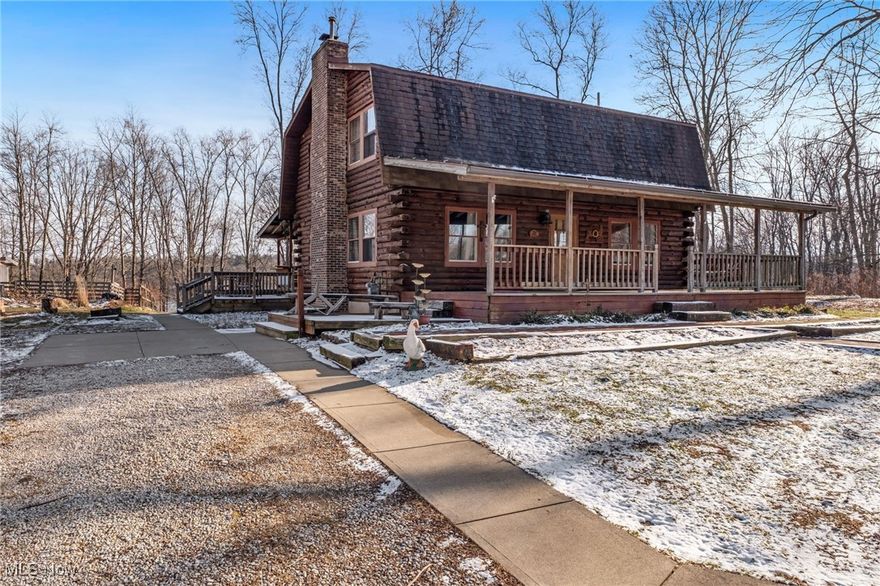 Situated on a 4.76-acre lot & sits on 500ft of frontage to the Mogadore Reservoir this 2-story, 5 bedroom, 2.5 bath log home is the perfect retreat from the hustle & bustle of everyday life. Surrounded by shade trees, a picturesque backdrop at the water's edge, access to the Buckeye Walking Trails, & an abundance of natural wildlife, a paved walkway guides you to the large, covered front porch with swings, setting the tone for the welcoming ambiance that awaits you inside. Inside this log home be greeted by an interior that exudes exquisite natural woodwork, striking log beams that grace the ceiling & many windows providing views from every room that enhance the connection to the beautiful surroundings outdoors. The floor plan creates a seamless flow between the living, dining, & kitchen, making it perfect for entertaining. The living room boasts a wood burning fireplace with gas starter for ease of use. The island kitchen, with cooktop, features ample cabinet & counter space plus pantry, along with essential appliances including a double wall oven. Ascend the open staircase from the living room to discover a generously sized master, designed to accommodate various furnishings with an abundant amount of closet space. The other 3 bedrooms are also well-proportioned & carpeted for comfort while a conveniently located full bath features a separate shower & classic clawfoot tub. The basement offers additional living space with 1 finished bedroom, a sizable rec room, & full bath. The laundry & mechanical room, complete with washer & dryer, ensures practicality for everyday living. A spacious rear deck overlooks the tranquil waters, perfect for enjoying leisurely mornings with a cup of coffee or take a break and fish, kayak, boat, or hunt(in season) right from your own backyard. Additional features include a commercial hot water tank, detached 3-car garage, greenhouse, & animal barn, all contributing to the home's functionality.