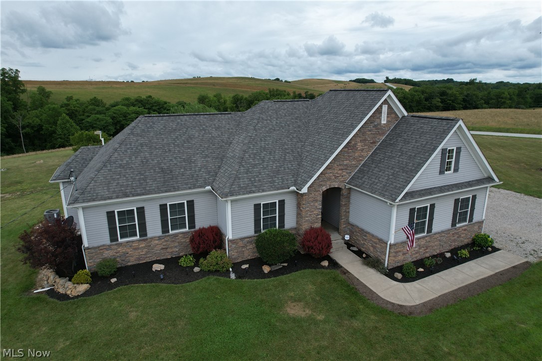 Tranquility doesn’t begin to describe the setting of this alluring 2013 custom home nicely situated on 7.5 acres with tremendous views! Vaulted ceilings w/ LED recessed lighting highlight from entry the open great room and elegant 2-tone kitchen with upgraded crowned cabinetry, island, solid surface counters & full set of appliances. Master suite features adjoining bath w/ double vanities & walk in closet as well as an additional closet! Full basement with bathroom option roughed in has poured walls and provides nearly 1800 additional sq ft of space to finish or enjoy now as recreation space! Dedicated laundry room w/ matching cabinetry and a 440 sq ft attached garage w/ windows & floor drain! The outbuildings provide tons of workspace and storage options including a 1000 sq ft structure w/ electric, concrete flooring & attached covered patio, adjoining covered lean to w/ overhead door plus another garage! Attractive stone faced exterior w/ vinyl siding, craftsman shutters, new landscaping, tile floors, new carpet, 2 panel doors, new bronze hardware, lighting, fans, faucets & more! New paint - ceilings, doors, trim & walls, new water heater. Pex plumbing w/ manifold system. Huge deck facing the back acreage where the sun sets beautifully into the hillside! Union school district. Only 12 miles from St. Clairsville and 23 miles from the Ohio River border, Wheeling, WV providing nearby shopping, parks, restaurants & entertainment!