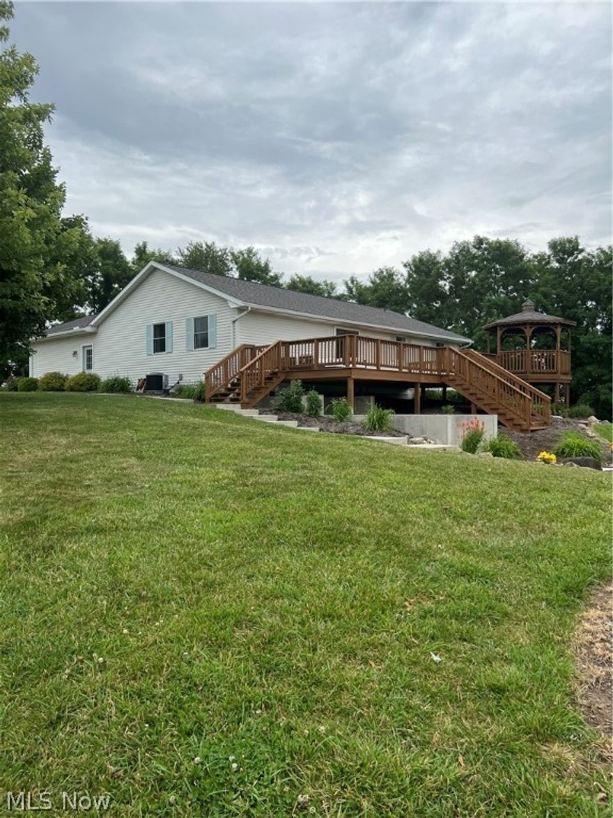 Check out this Beautiful Country Ranch home with a Hilltop Setting and views of Holmes County rolling hills on 5.5 Acres. This home is currently operating as a Vacation Home and is turn-key.  Located just minutes from Mohican Country and Amish Country.  Enjoy nature and relax on the expansive back deck with attached gazebo, custom patio with firepit or the cozy front patio area.  As you enter the home you are greeted with an open concept and mid-century modern de cor.  The updated kitchen is bright and invites you in for the gatherings.  In the living room is a brand new custom fireplace and seating along with a sliding glass door that leads from the living room to the large back yard deck.  Down one short hallway you will find a guest bathroom and 2 bedrooms with a fun mural, hand-painted by a local artist. Down a separate hall is the primary bedroom that boast of color and character, a complete on-suite bathroom. Large and spacious first floor laundry and mud room is off the 2 car at