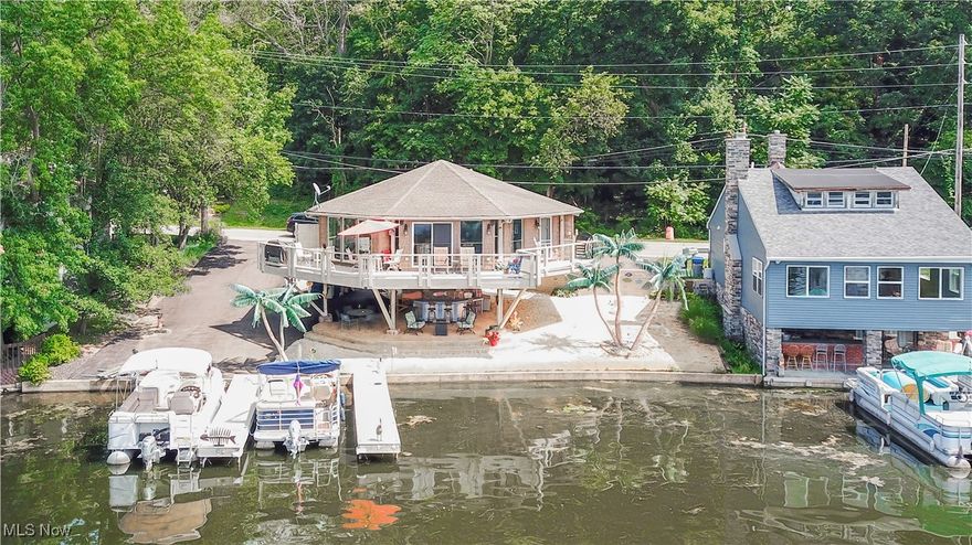 Paradise found! This one-of-a-kind, custom-built octagon-shaped pedestal home offers unmatched design and breathtaking waterfront views on Portage Lakes. Inspired by post-and-beam barn construction, a single center post anchors the floor and roof beams, extending outward to panoramic windows and soaring cathedral ceilings throughout. At the heart of the home, the kitchen features a wrap-around counter with built-in stools, stainless steel appliances, granite countertops, solid birch cabinetry, under-cabinet lighting, and a reverse osmosis drinking water system. Brazilian maple floors add warmth and elegance. The open-concept great room flows to the primary suite with a spacious walk-in closet and a luxury bath, along with two additional bedrooms and a full main bath. Step outside to enjoy your sandy beach, two private docks, a jet ski lift, and a custom concrete patio, perfect for entertaining by the water. Recent upgrades include a brand-new asphalt driveway (June 2025) with ample parking, newer leaf-filter gutters, a newly power-washed and stained upper deck (May 2024), a new catwalk to the driveway (2020), and updated primary bath sinks and cabinetry (2021). With guest parking, a jet ski lift, and every detail thoughtfully maintained, this truly is a turn-key lakefront retreat. Don't miss your opportunity to own this beautiful, one-of-a-kind lakehouse!