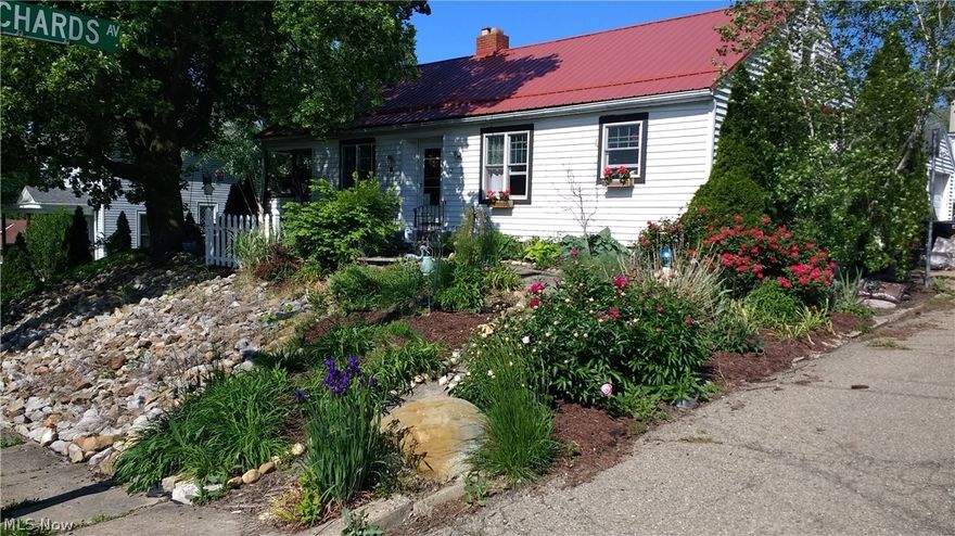 Charming home waiting for your personal touches.  Lots of updates including newer metal roof, gas tankless hot water heater, updated electric and plumbing, vinyl siding and windows except one bedroom, kitchen, and built ins added. This home offers kitchen with oak cabinets, stove and refrigerator, dining room, living room with wood burning fireplace, two bedrooms, first floor laundry, updated bath with steam shower and door to rear deck with privacy fencing and area for a hot tub.  Deck offers Pergola and gas heater for cool evenings.  Covered side porch.  Mature landscaping with two raised veggie beds, stereo system in garage with speakers to stay, along with curtains/drapes and area rugs.  One car detached garage.