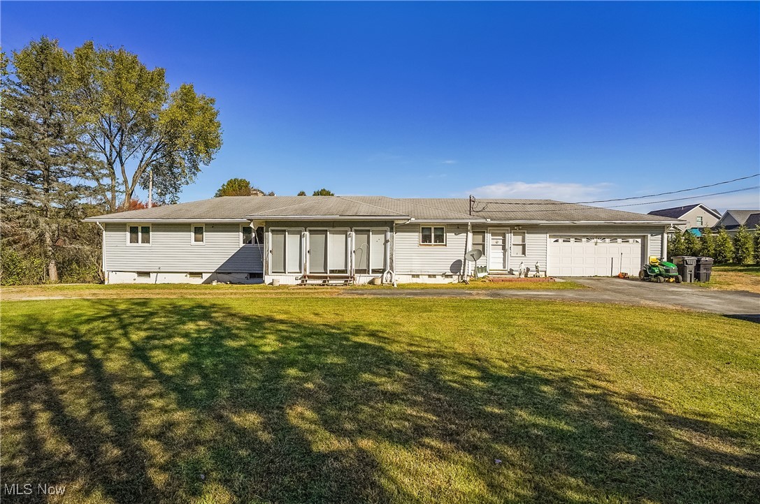 Welcome to a rare investment and lifestyle opportunity in the heart of Canfield! Perfectly situated on just under an acre in a highly desirable area known for its top-rated schools, peaceful surroundings, and easy access to shopping, dining, and major routes, this sprawling 5-bedroom, 2-bath vinyl-sided ranch offers endless potential for families and savvy investors alike. The bright sunroom with six sliding glass doors, a breezeway leading to a private back deck, and stunning wooded views create the perfect blend of comfort and nature. The main level features a fully equipped kitchen with all appliances, formal dining room, spacious living room, three bedrooms—including a generous master—and a beautifully updated full bath. The lower level offers a separate entrance and is ideal for an in-law suite, rental income, or multi-generational living, with a second full kitchen, two additional bedrooms, a cozy family room with fireplace, laundry, and storage. Outdoor living is enhanced by a walk-out patio, while the 2-car attached garage (with its own furnace and hot water tank), plus 3-car and 4-car detached garages, make this a dream for car enthusiasts, contractors, or anyone needing space for equipment or hobbies. Additional perks include a wood-burning alternate furnace for energy savings and public water/sewer available at the street. Whether you're looking for a spacious family retreat or an income-producing property, this Canfield gem checks all the boxes—schedule your showing today before it's gone!