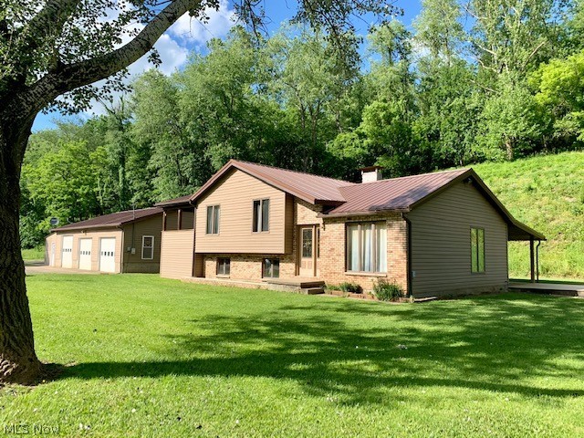 Only 5 miles from Interstate 70, yet so private! If you are looking for space for your home based auto sales/repair or woodshop type business, look no further! Very nice tri-level home with many updates. Vaulted ceilings, many floor to ceiling windows and new carpet in bedrooms. New sliding glass doors with built in blinds in master bedroom lead to 240 sq. ft. private covered deck, complete with ceiling fans. You will love the additional storage areas above and below this deck. For additional outdoor living, there is also a second covered deck area on the back of the home. New central air 2019, new 200 AMP electric and the house and both garages received new metal roofs in September 2019. Now lets talk about the monster garage! Formally Mac's Auto, this garage has many possibilities! Ten foot ceilings, 3 garage doors (two are 8 ft. high, one is 9 ft. high. All are 10 ft. wide), hydraulic car lift, wood burner and a designated office space with mounted gas (propane) heater. Garage has s