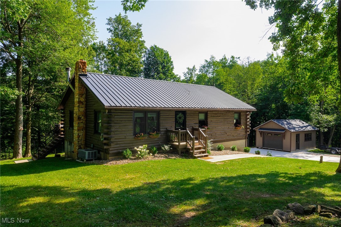 On-site auction Thursday, September 4th at 6:00 PM. Here is a very nice, move in ready 3-bedroom, 2-bath log home on 7.2 acres that has had many updates done and is ready for your enjoyment. Some of the improvements include a new steel roof, Yoder replacement windows and doors, and inside there is a lot of flooring that has been replaced. The kitchen is very spacious and has all the newer appliances that will sell right with the property. Walk out of the kitchen with a cup of coffee and onto a very nice Trex patio that allows you to watch the deer that are frolicking in the wooded area. Downstairs you have a connecting garage along with laundry area and a wood stove that can easily heat your entire home in the coldest winter months. This, along with electric heat, makes it very easy to maintain. It is equipped with Central air for the summer months and going outside you have new sidewalks and a nice new concrete driveway along with a newer 18x24 shop/storage barn that is ready for your tools and equipment. Excellent hunting in the roughly 6-acre wooded area that could be cleared for pasture if you so desire. Room for chickens, goats, dogs or whatever you wish on this quiet country road, close to everywhere but very secluded. As an added bonus, an underground electric dog fence with two collars will stay for your furry friends. Don't miss this very affordable log home in the hills of Western Holmes County.