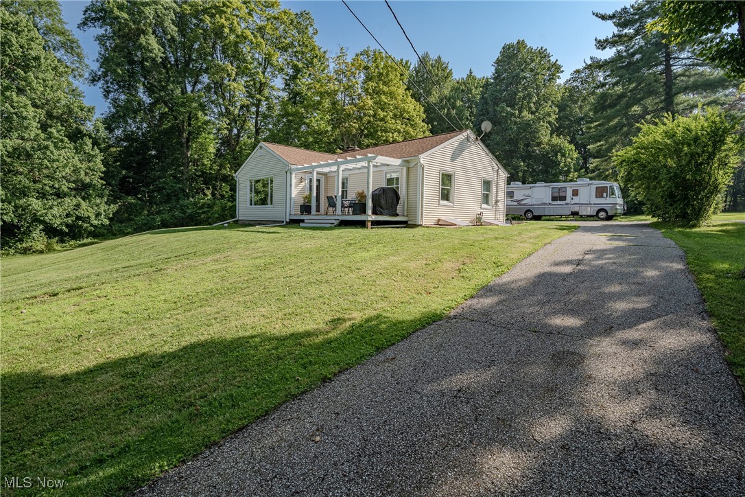 Welcome to 7991 Chagrin Rd – A Charming Ranch Retreat in Scenic Chagrin Falls! Perched atop a gentle hill on nearly 2 acres of lush land, this delightful ranch-style home combines cozy charm with spacious living—all just 5 minutes from the heart of downtown Chagrin Falls. Step onto the inviting front deck, perfect for sipping morning coffee while enjoying peaceful views. Inside, you’re greeted by gleaming hardwood floors and a light-filled, oversized living room complete with a huge picture window, wood-burning fireplace, and direct access to the side yard—ideal for entertaining or unwinding. The kitchen is a true standout with its stone accent wall, tile backsplash, high-quality cabinetry, and a full set of appliances ready to inspire your inner chef. Down the hall, you’ll find three comfortable bedrooms, a full bathroom, and a laundry closet for added convenience. French doors from the mudroom open into a sunny bonus room with patio access—perfect as a home office, gym, or playroom. The home also features an attached 1-car garage plus a carport, offering plenty of parking and storage flexibility. Head downstairs to the refreshed full basement with newly refinished flooring and a brand new full bath—a fantastic spot for recreation, movie nights, or hobbies, with extra room left over for storage. Whether you're looking for space to spread out or simply enjoy the peaceful surroundings, this hilltop gem offers it all. Don’t miss the chance to own a slice of tranquility just minutes from shops, dining, and the charm of downtown Chagrin Falls!