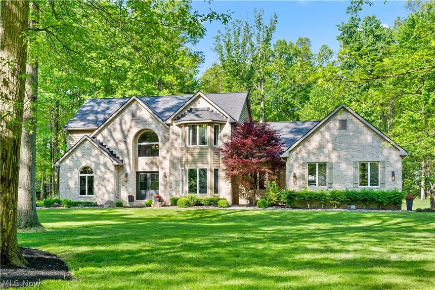 Experience privacy, elegance and timeless craftsmanship at 5130 Hecker Dr, in Richfield Ohio located with in the highly sought-after Revere School District. Nestled on a 7.34 acre setting , this property welcomes you with a long winding paved driveway that creates a grand approach while offering the peaceful surroundings and seclusion that are difficult to find. Inside, quality details and thoughtful updates are evident throughout. The  updated kitchen serves as the heart of the home and features high-end Jenn-Air appliances, abundant workspace and an ideal layout for both everyday living and entertainment. Flowing seamlessly from the kitchen is a custom dry bar area leading into the formal dining room, highlighted by elegant custom Craftsman style trim that creates a sophisticated space for hosting gatherings and holiday dinners. Natural hardwood flooring carried through out the main living area adding warmth and character. The dramatic two-story living room offers an impressive focal point with soaring ceilings and a stunning brick fireplace enhanced with a wood-burning insert, creating an inviting space to gather year-round. The first floor laundry room includes a sink and it's own private exterior entrance for added convenience. Retreat to the luxurious owner's suite featuring a newly remodeled spa-inspired bathroom complete with heated marble flooring and an Italian stone soaking tub perfectly positioned beneath the new oversized picture window overlooking the expansive backyard and picturesque property. A spacious office featuring rich wood paneling and an attached secondary locked room ideal for securing valuables, sensitive files or creating a private storage area. Upstairs, the thoughtfully designed floorplan includes an on-suite bathroom and two additional bedrooms connected by a Jack-And-Jill bathroom, providing comfort and privacy. Car enthusiasts and hobbyists will appreciate the oversized three-car garage, which features new insulated garage doors.