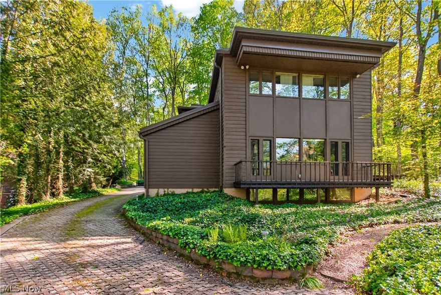 Tucked into the hillside with breathtaking wooded and creekside views from nearly every window, this completely remodeled 4-bedroom, 2.5-bath retreat offers the perfect blend of nature, architecture, and modern comfort. Designed with striking mid-century modern touches throughout, the home is filled with natural light thanks to an abundance of windows that bring the outdoors in and create true “tree house” vibes at every turn. The peaceful, retreat-like atmosphere is enhanced by thoughtfully selected natural materials and calming design elements that make this home feel like a private sanctuary. Enjoy seamless indoor-outdoor living with an entertaining patio, a front balcony perfect for morning coffee and birdwatching, and park-like views from the home’s elevated setting. Inside, the finished basement adds valuable living space along with a workshop area and abundant storage throughout the home. The garage is equipped with a 240-volt, 50-amp outlet for Level 2 EV charging and additional storage space for convenience. Even the exterior has been designed for ease, featuring a 100% maintenance-free yard so you can spend more time enjoying the setting and less time maintaining it. Additionally, the roof is a 24 gauge standing seam metal roof with leaf guards. A rare opportunity to own a one-of-a-kind nature-inspired retreat where modern design and peaceful surroundings exist in perfect harmony.