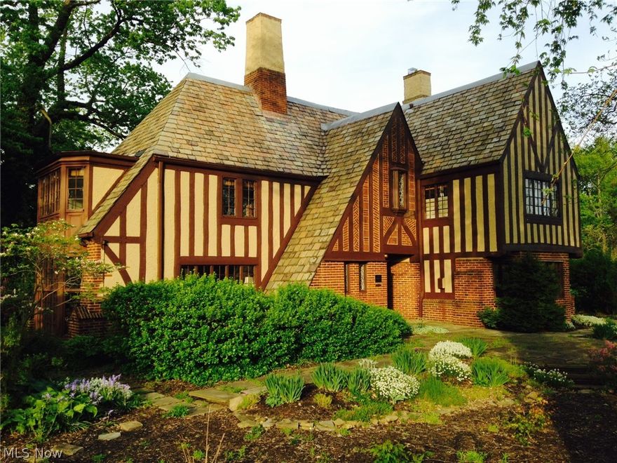 This special English Tudor is one of five contiguous Bloodgood Tuttle-designed "Shaker Heights Landmark" houses on double lots. Situated on a half acre of fragrantly-planted gardens, architectural features include pegged half-timbering, patterned brickwork, and graduated slate roofing. All main floor spaces spoke off the octagonal Entrance Hall. The bright Living Room boasts a classically-inspired fireplace surround, garden-view bay window, and French doors to the terrace with lily pond. There are built-in bookcases and a vaulted ceiling in the Library, currently used as the Dining Room. The octagonal Dining Room, re-purposed as the Family Room, opens directly off the Kitchen, and features stained cabinetry and woodwork. The renovated Eat-in Kitchen offers granite and hardwood countertops and SS appliances.  Upstairs a private Master Suite has a fully renovated bath with walk-in rain shower. Multiple closets and original built-in cabinetry provide great storage. Three more large bedroo
