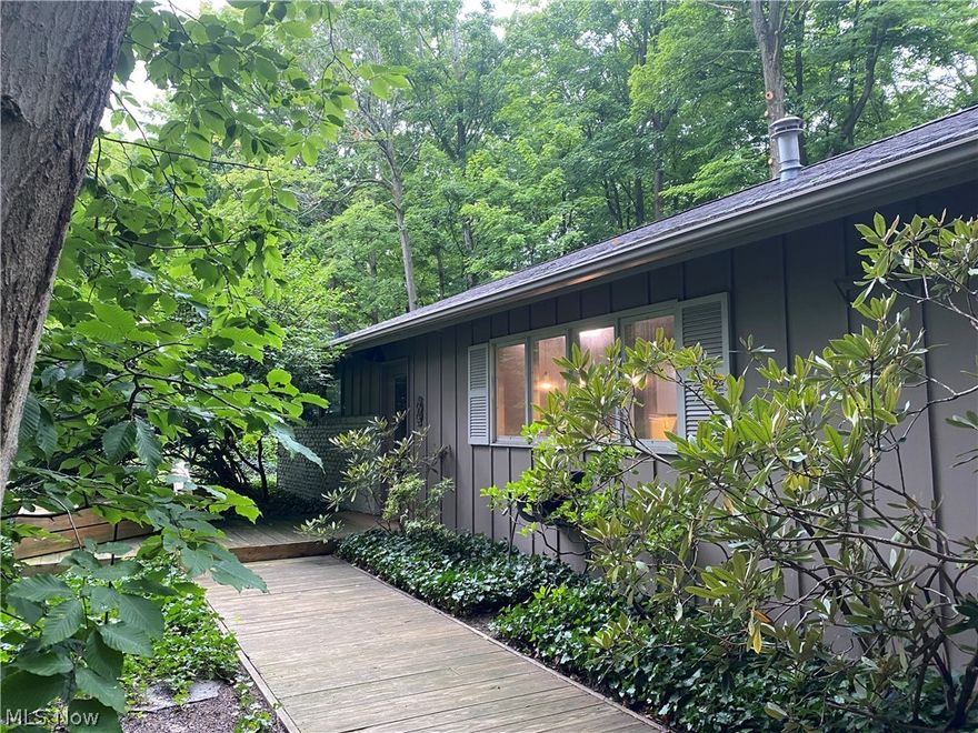 First floor living in the heart of Mayfield Village is waiting for you! Entertaining is easy with a dining room and open concept living room/family room which offer full, expansive views of the outdoors and a double-sided fireplace for those cool-weather nights. This unique home features a primary en-suite with a convenient half bath and walk-in closet.  The eat-in kitchen has stainless steel appliances, pendant lighting, Corian countertops, and a buffet counter with additional storage.  Enjoy the wooded privacy on the double deck with your family and friends.  Two car attached garage. Refrigerator in garage stays. Prime location and just minutes from shopping,  grocery stores, hospital, schools and the North Chagrin Reservation. This mid-century home awaits your finishing touches!